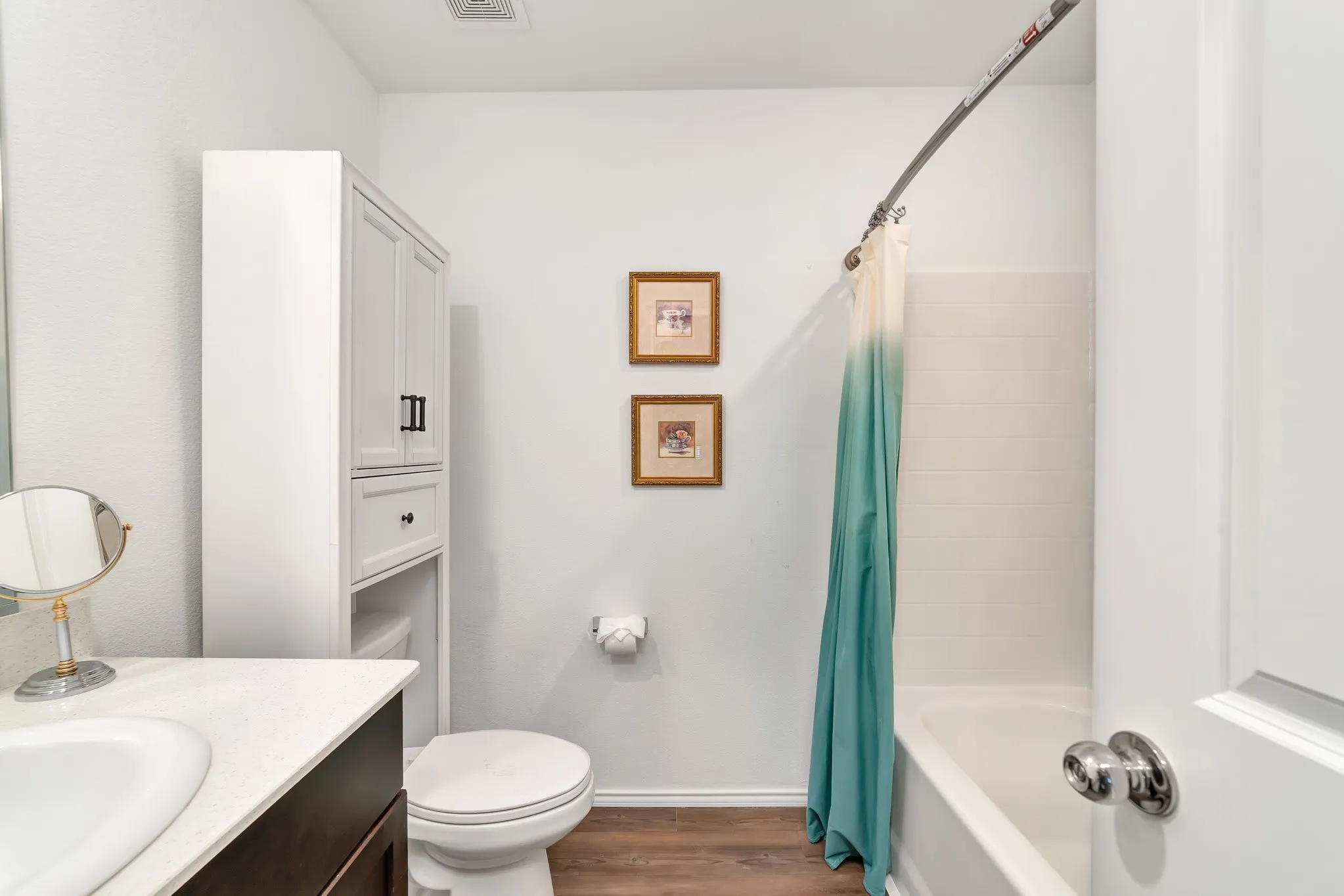 Bathroom featuring a white vanity with an integrated sink, dark wood-finish cabinetry, a white countertop, and wood-finish flooring