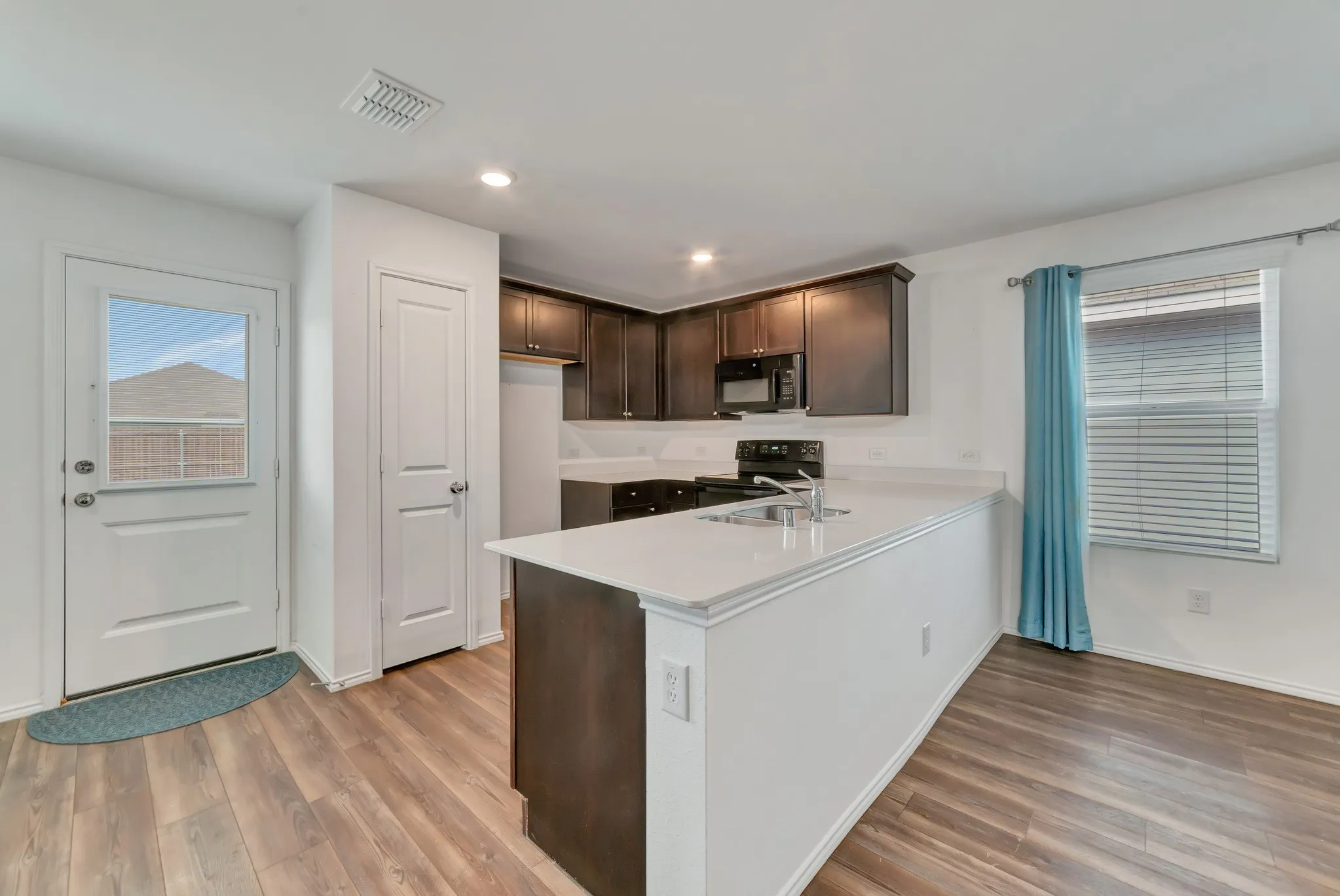 Kitchen featuring dark wood cabinetry, white countertops, and wood-finish flooring