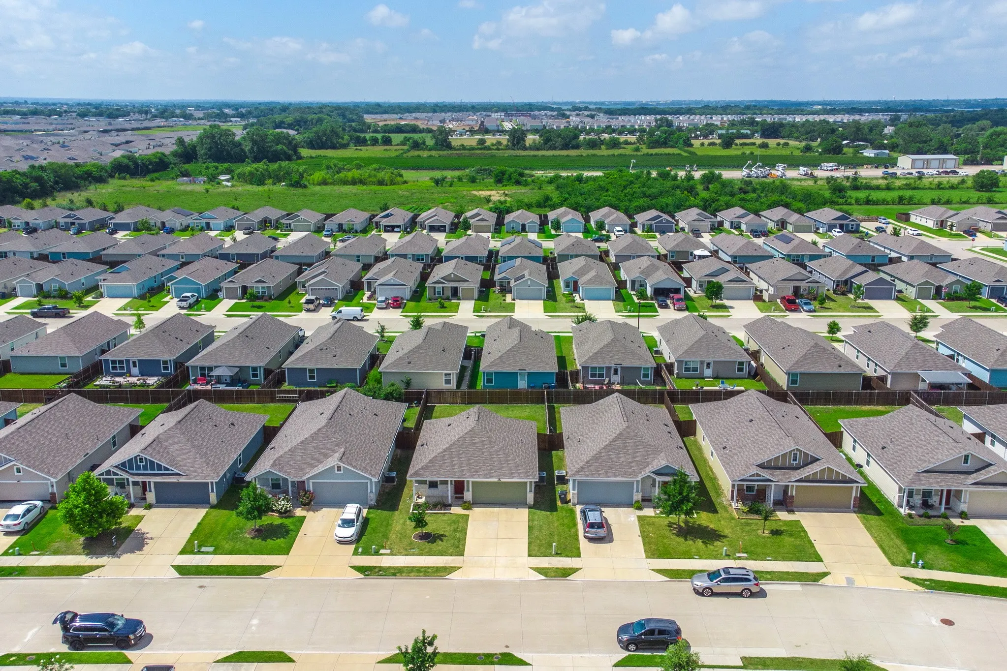 Residential community featuring uniform single-story homes with pitched roofs, front-facing garages, and landscaped front yards