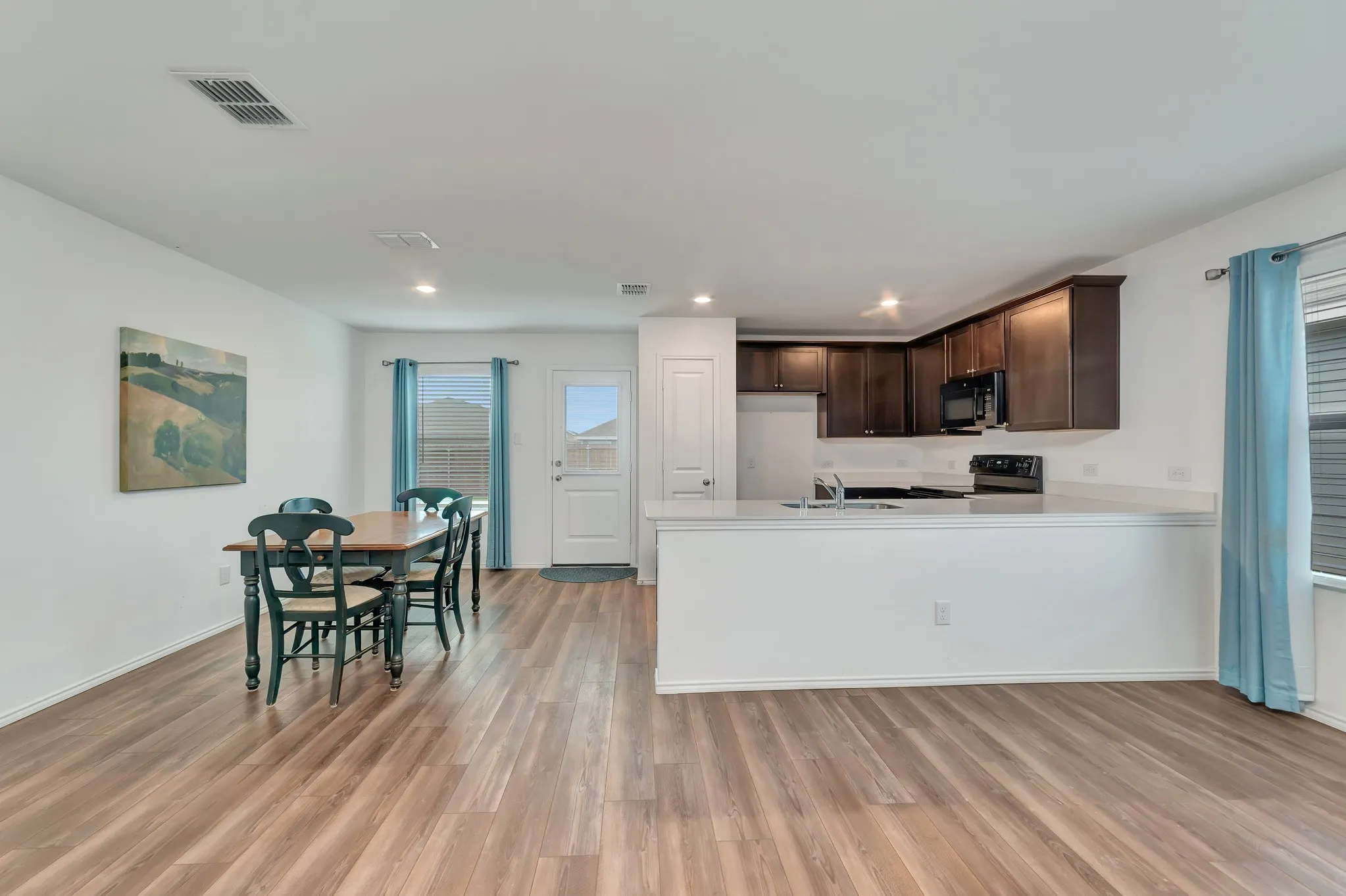 Open-concept common area featuring wood-finish flooring, recessed lighting, and white walls