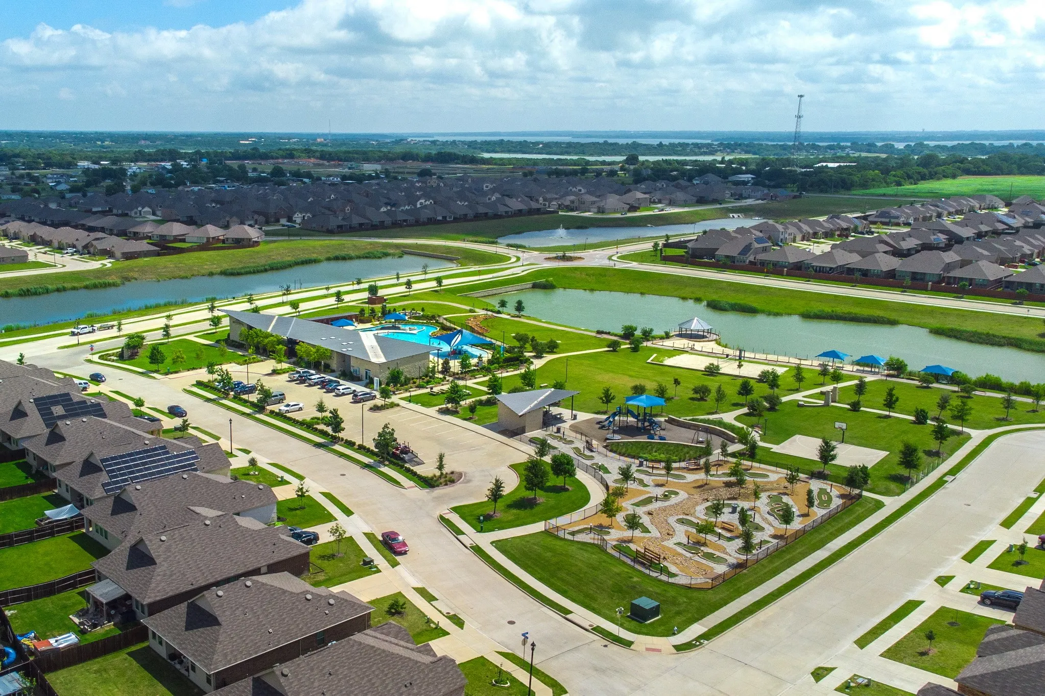 Expansive community featuring a large aquatic center with multiple pools, a modern playground, a spacious park area, and scenic ponds