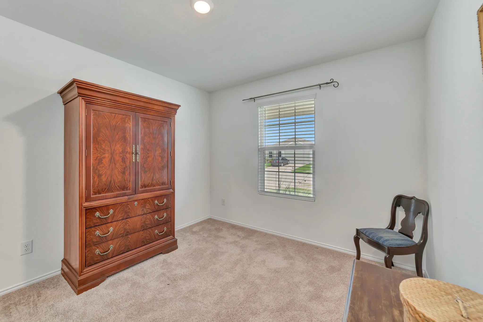 Carpeted room with white walls, a single window featuring blinds, and a built-in ceiling light fixture