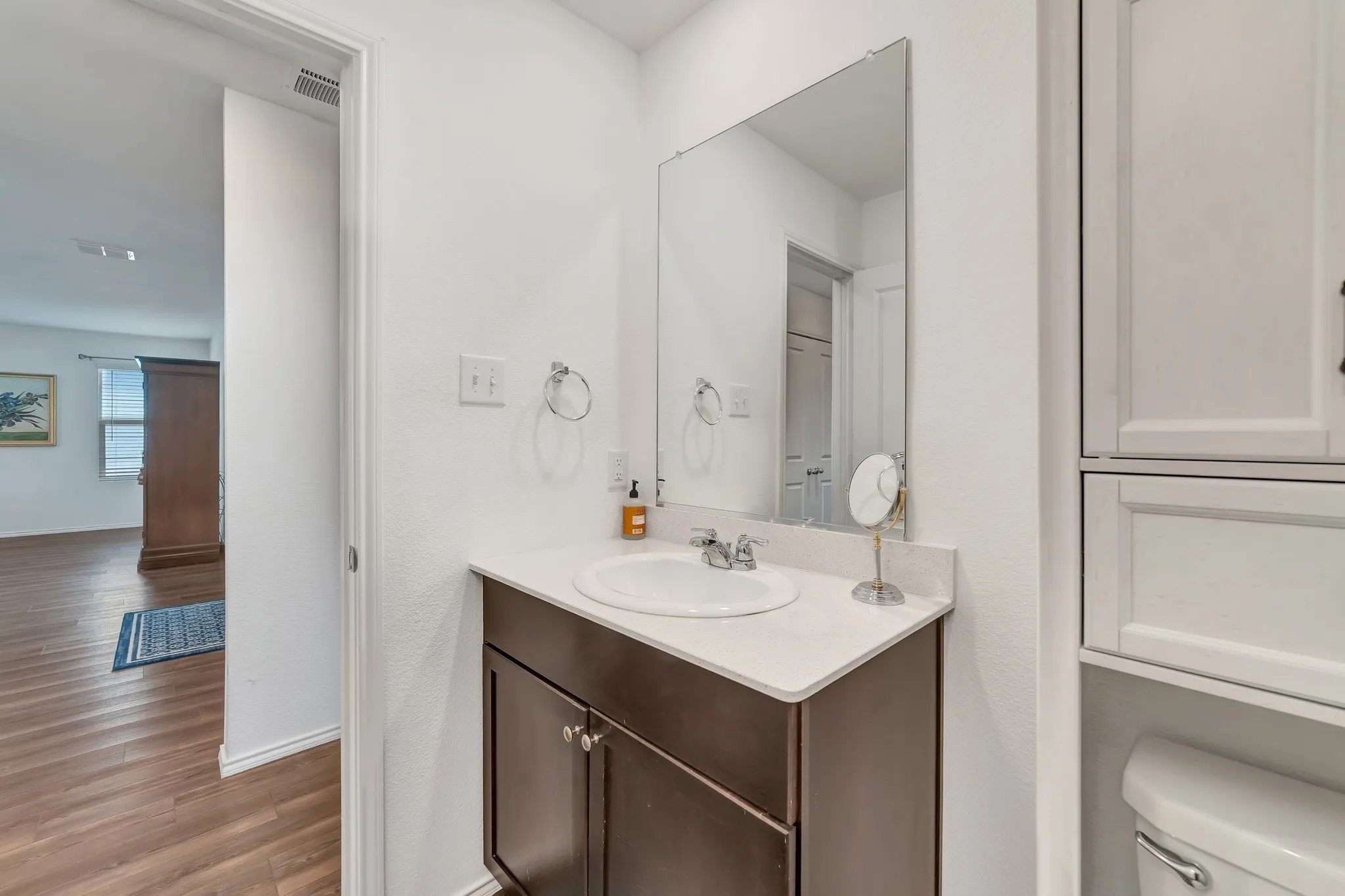 Bathroom vanity featuring a white oval sink, chrome faucet, and engineered stone countertop