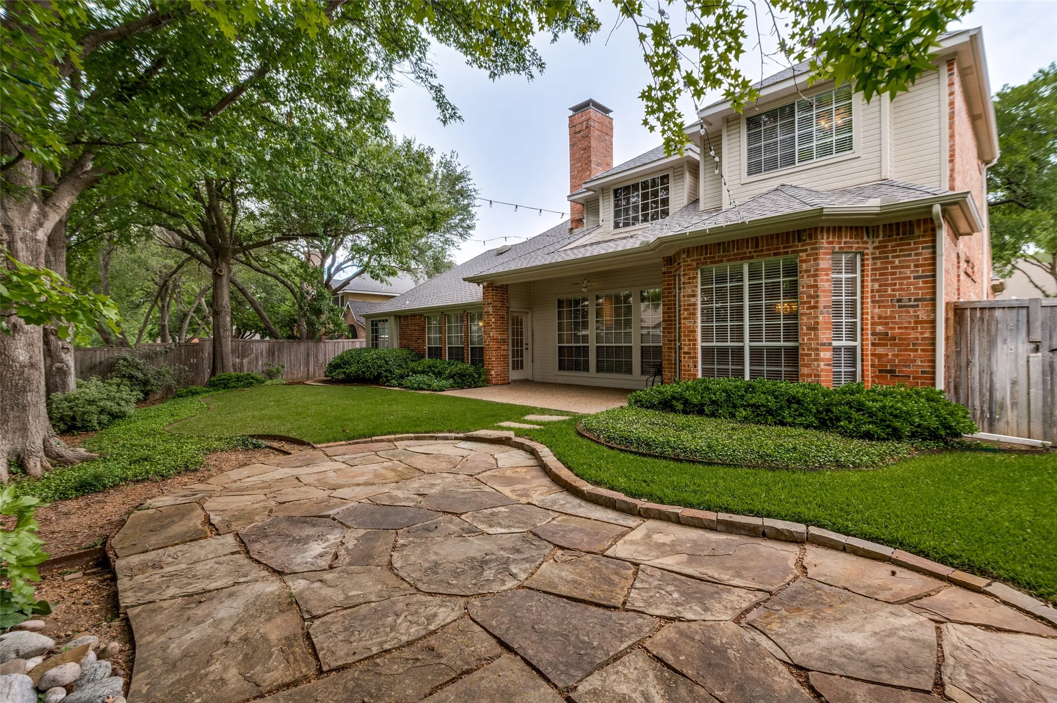 Flagstone patio with a water feature is surrounded by beautiful landscaping and completes the out door living space.
