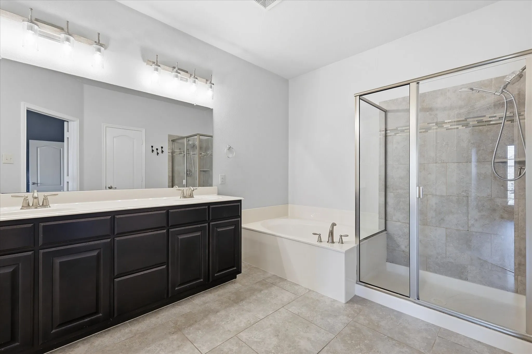 Spacious bathroom featuring a dual vanity with dark wood cabinetry, white countertop, and integrated sinks
