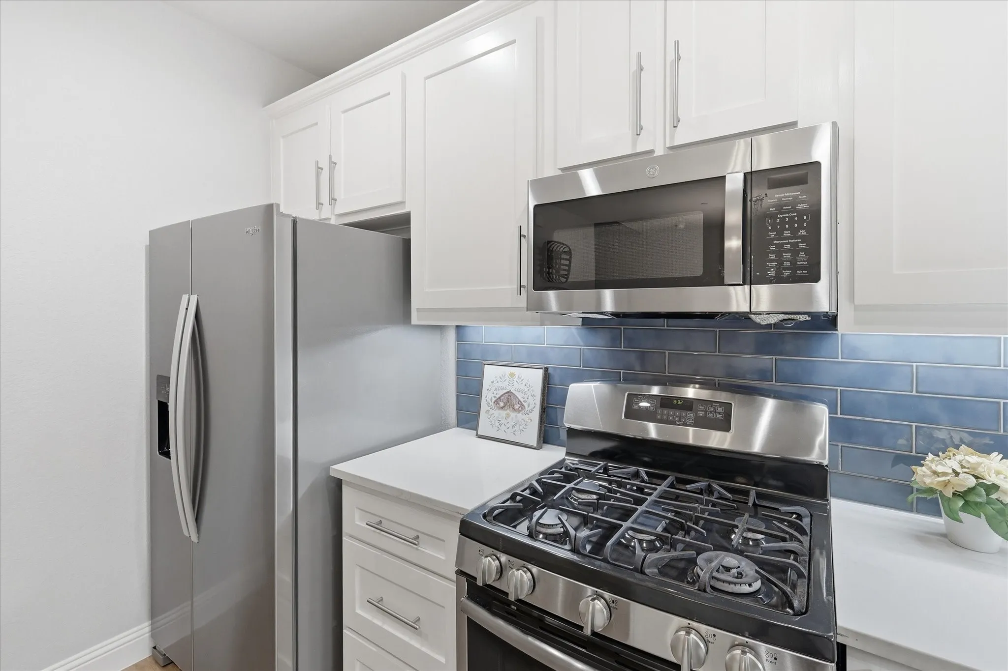 Kitchen featuring white shaker-style cabinetry, stainless steel appliances, a subway tile backsplash, white countertops, and a gas range