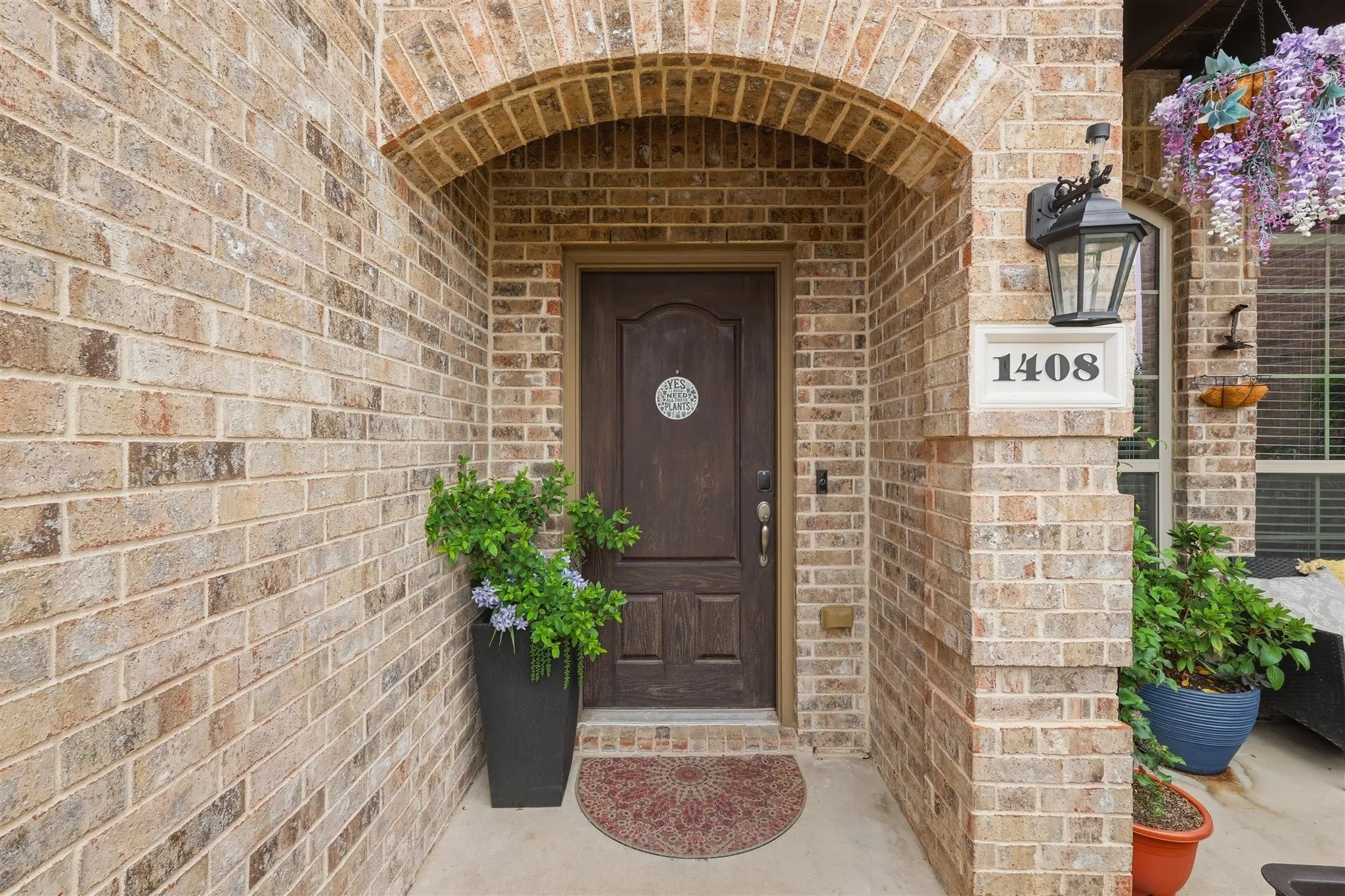 Arched brick entryway featuring a dark wood paneled door with decorative glass inlay
