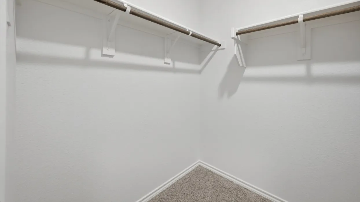 Corner closet space featuring white walls, white baseboards, and neutral-toned carpet