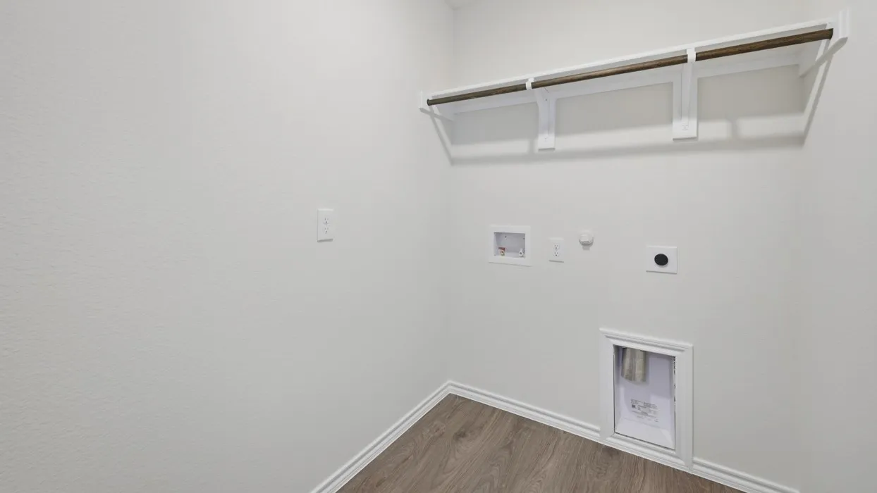 Utility space featuring wood-finish flooring, white walls, built-in shelving, and laundry hookups