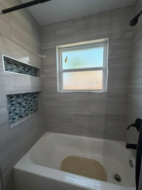 Bathtub with light-toned tiled surround