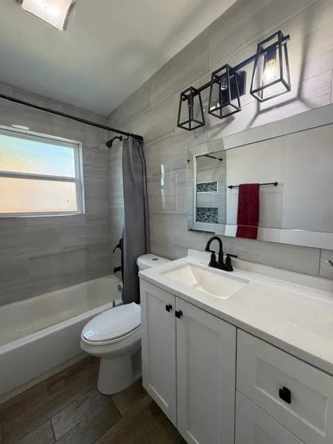 Modern bathroom featuring a white vanity with integrated sink, a dark hardware faucet, and a contemporary three-light fixture