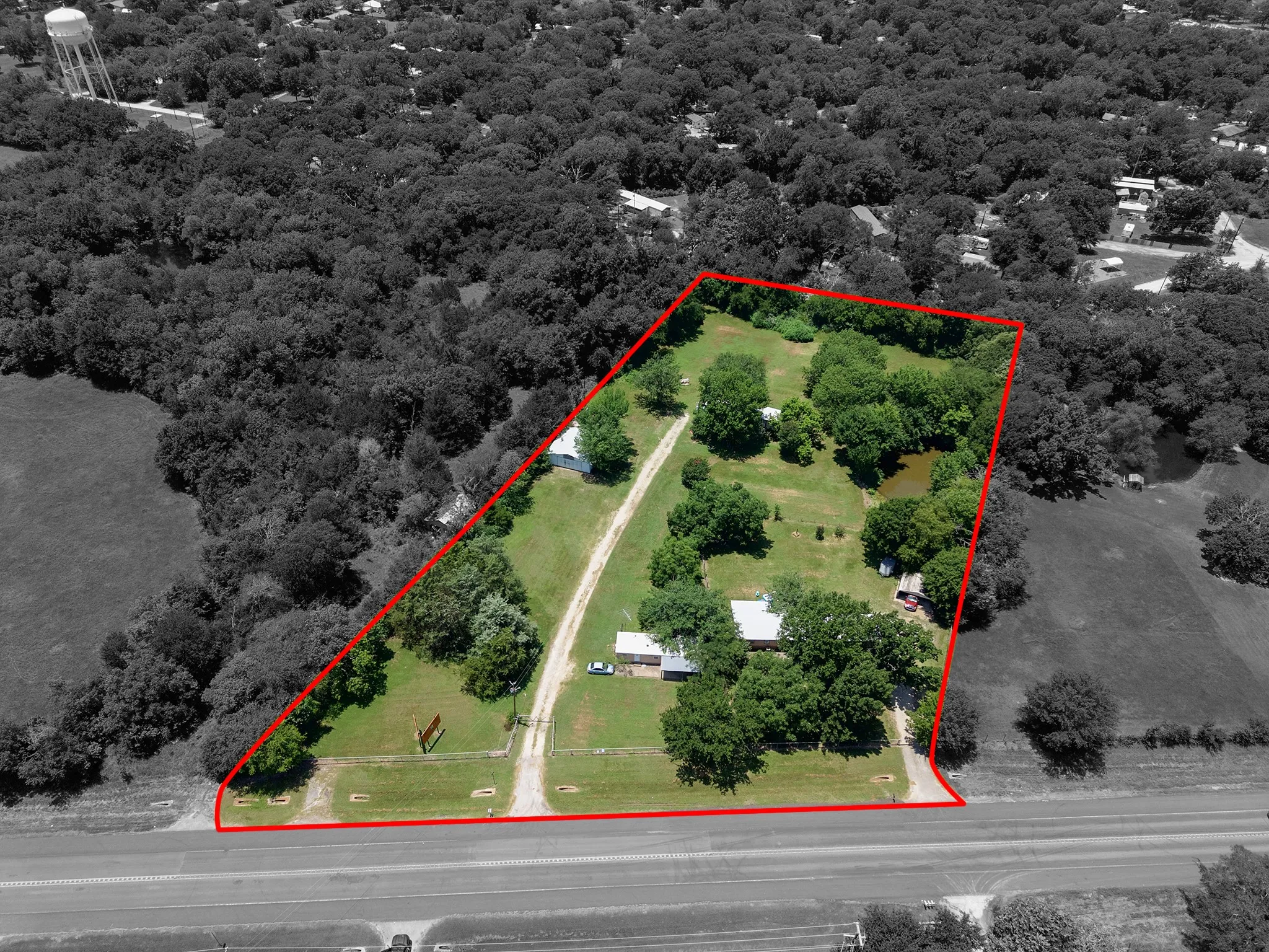 Expansive acreage featuring multiple structures, mature trees, a private pond, and direct road frontage