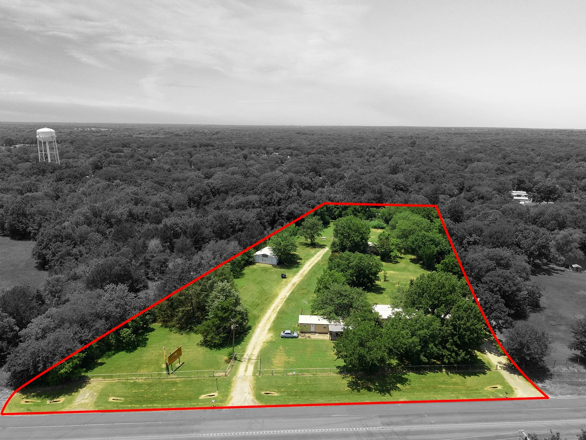 Expansive parcel featuring mature trees, a long driveway, and a residential structure with an outbuilding