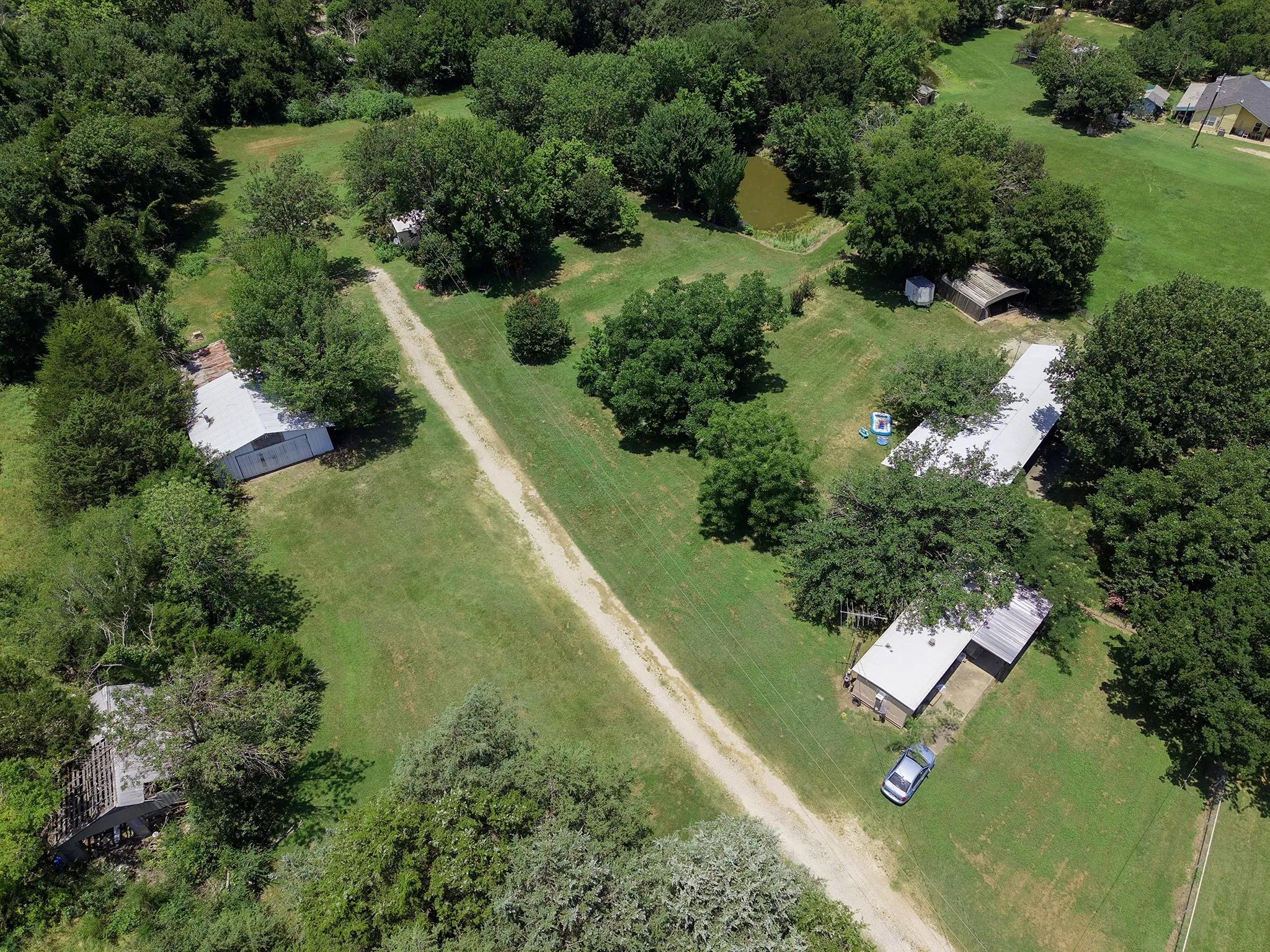 Expansive property featuring multiple structures, a private pond, and mature tree coverage