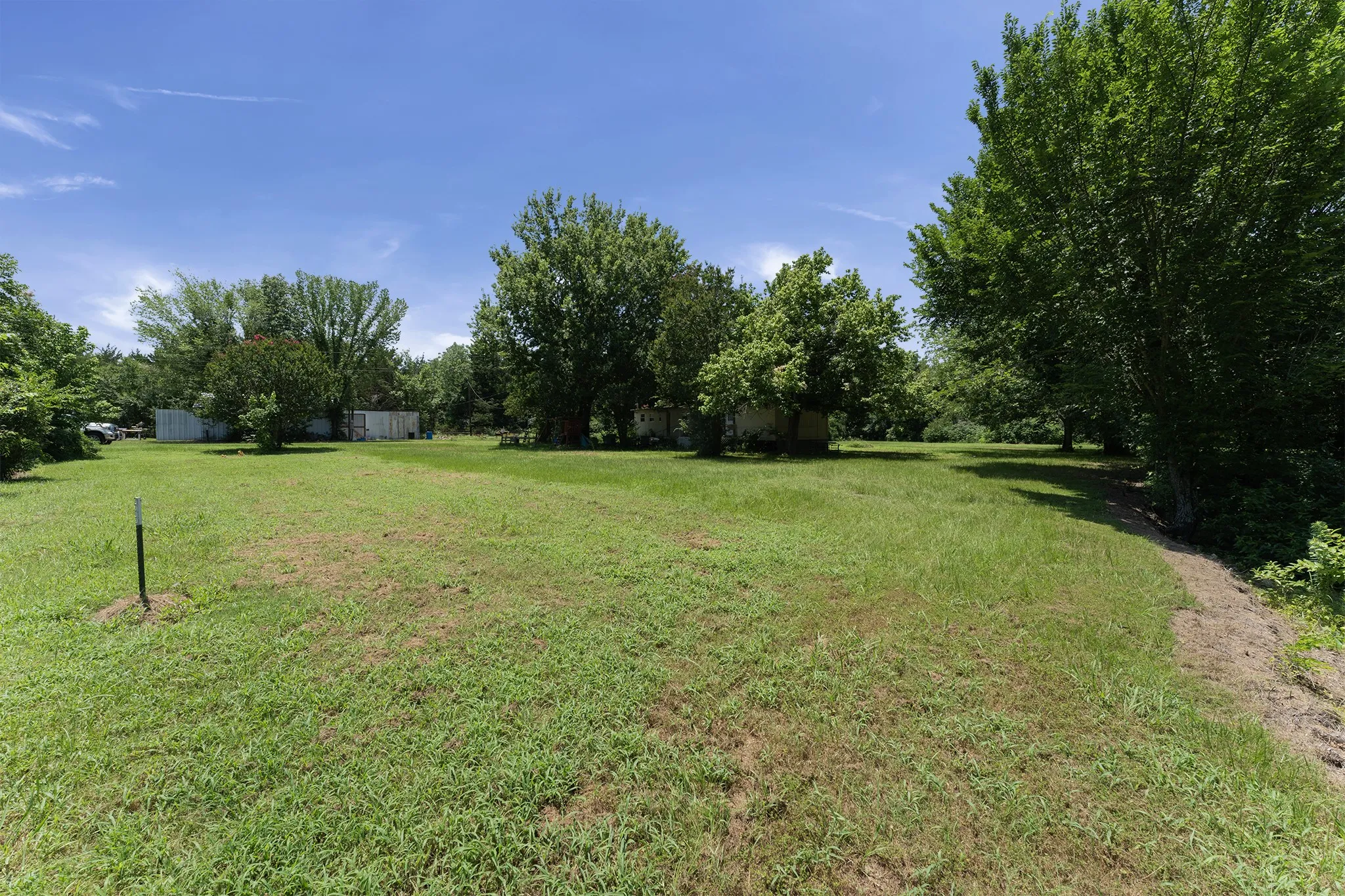 Expansive grassy lot bordered by mature deciduous trees