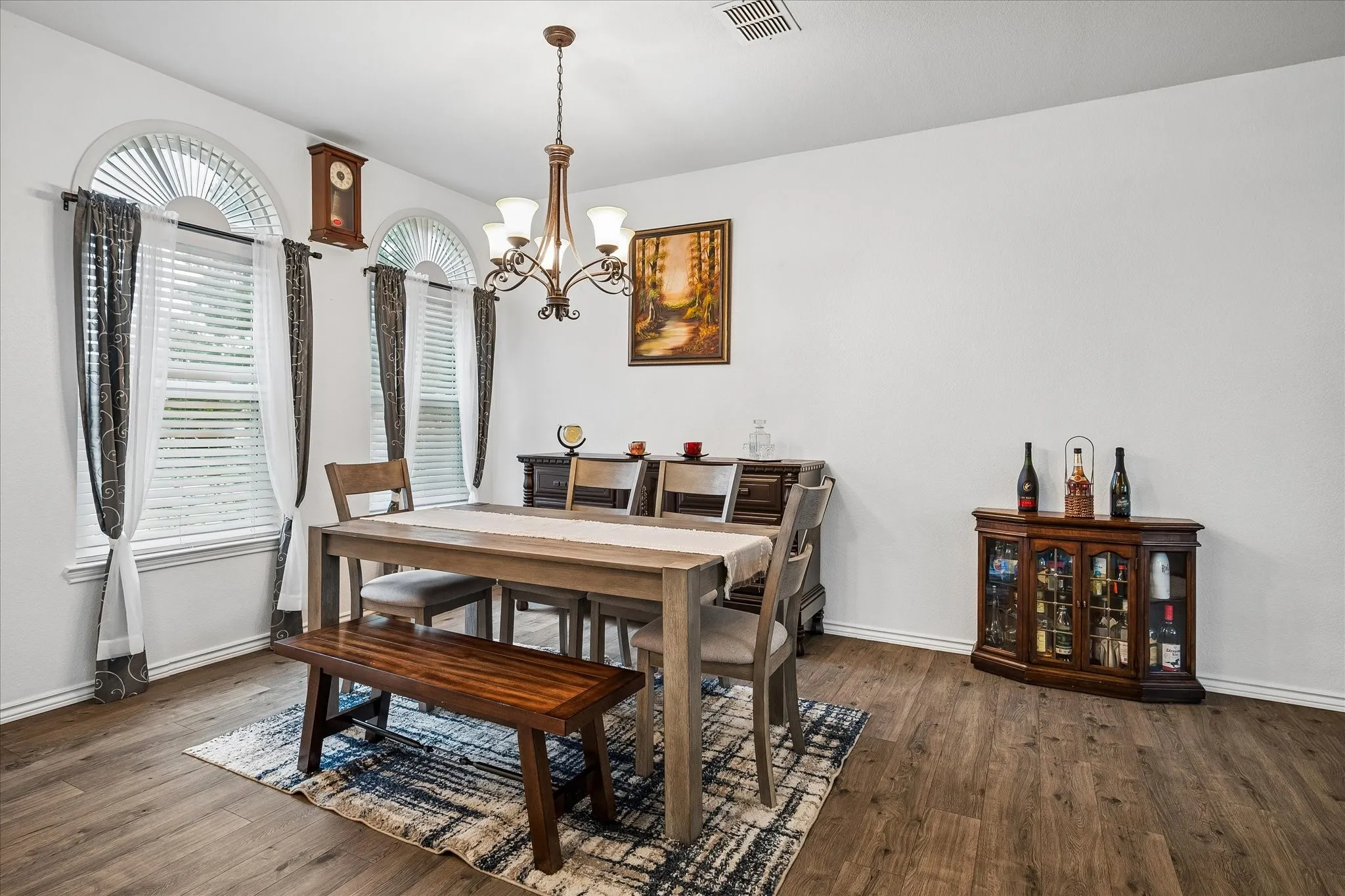 Dining area with wood-finish flooring, arched transom windows, and a chandelier