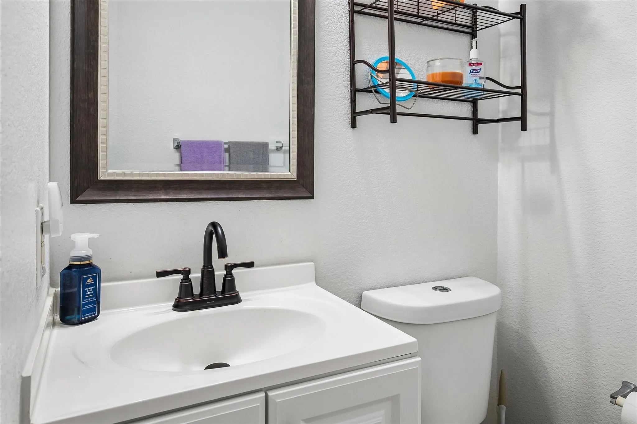 White vanity with an integrated sink, oil-rubbed bronze faucet, and framed mirror