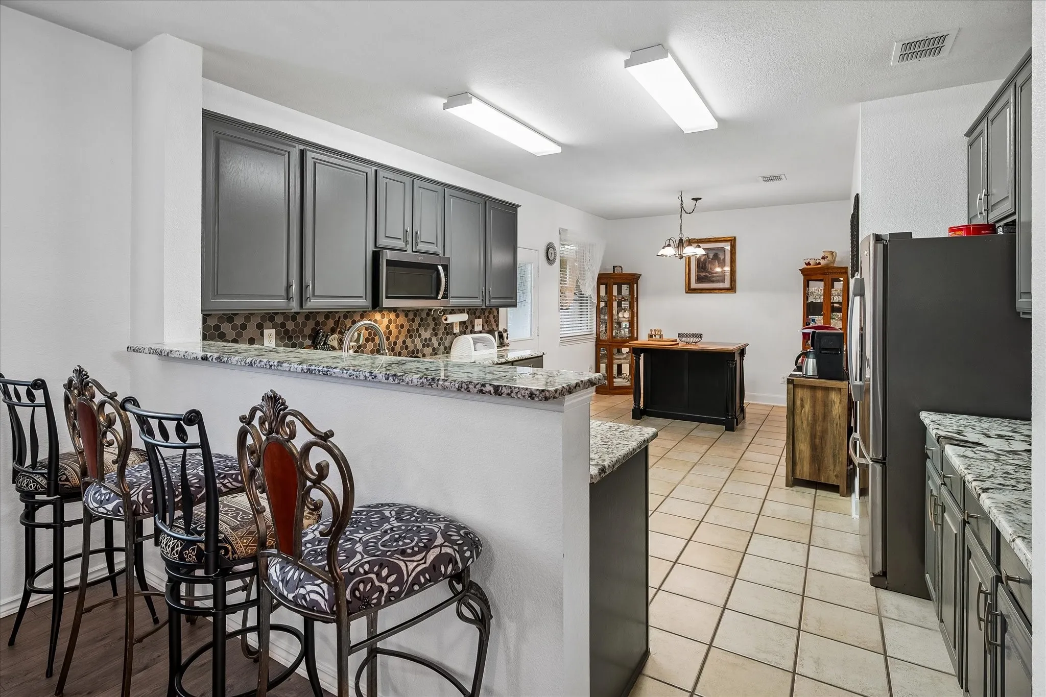 Kitchen featuring gray cabinetry, light granite countertops, a built-in microwave, and tile flooring