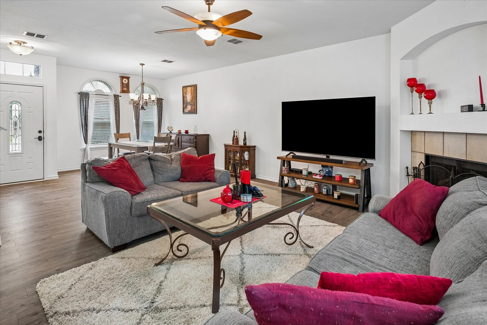 Wood-finish flooring throughout, ceiling fan with integrated lighting, and an arched entry