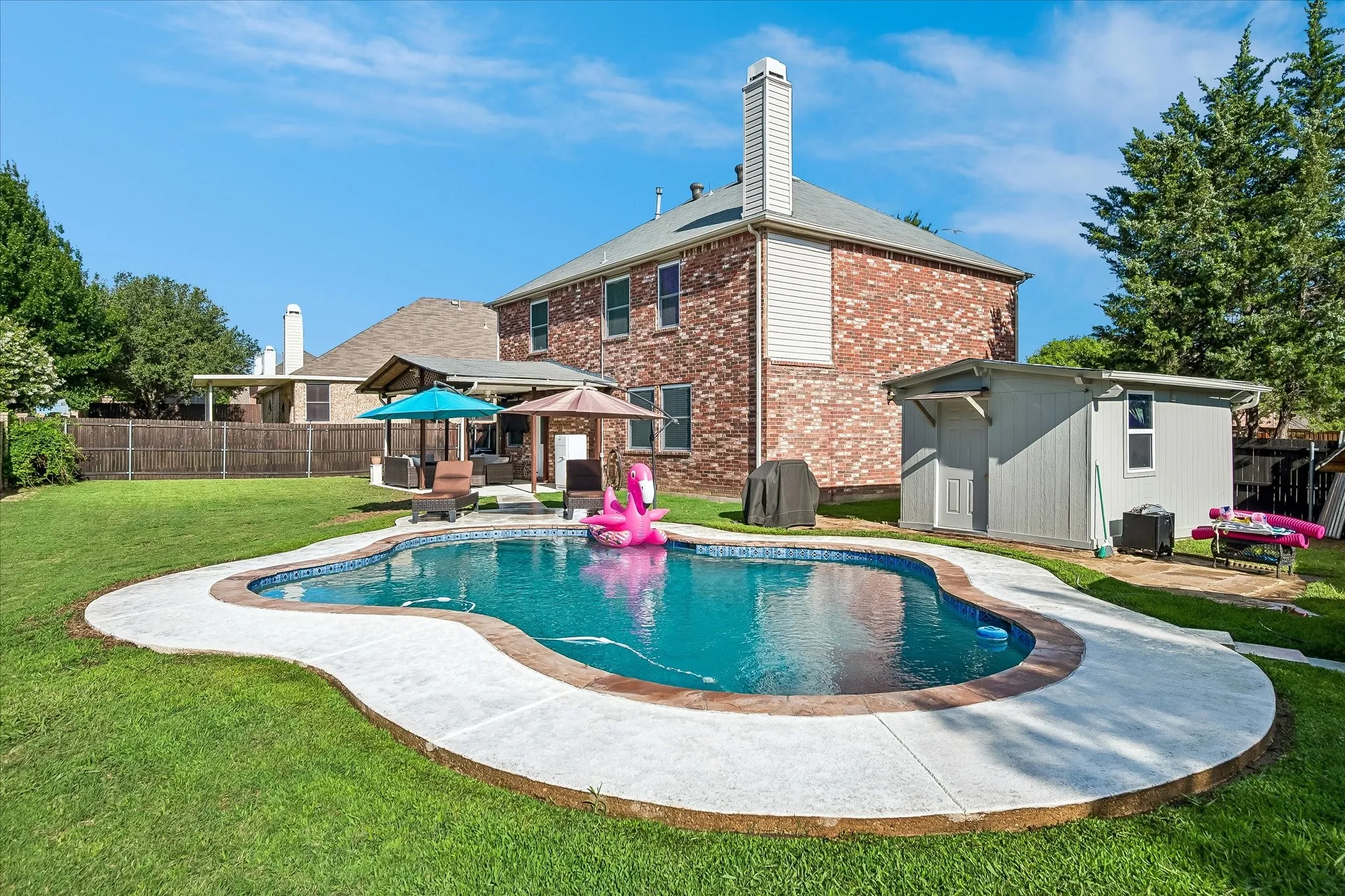 Manicured lawn with a freeform swimming pool featuring a concrete surround