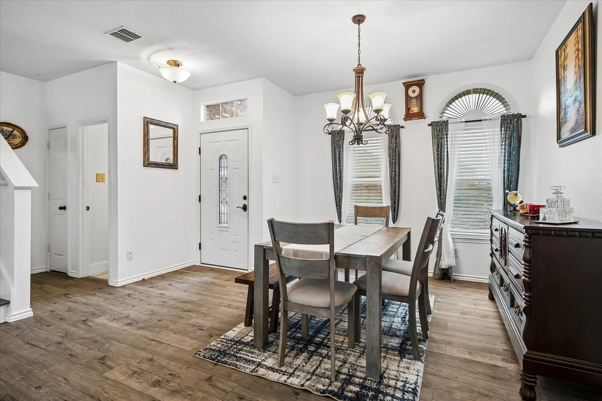 Wood-finish flooring, white walls, and a decorative chandelier