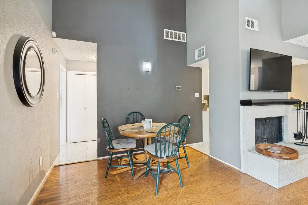 Wood-finish flooring throughout, featuring a white brick fireplace with a dark mantel