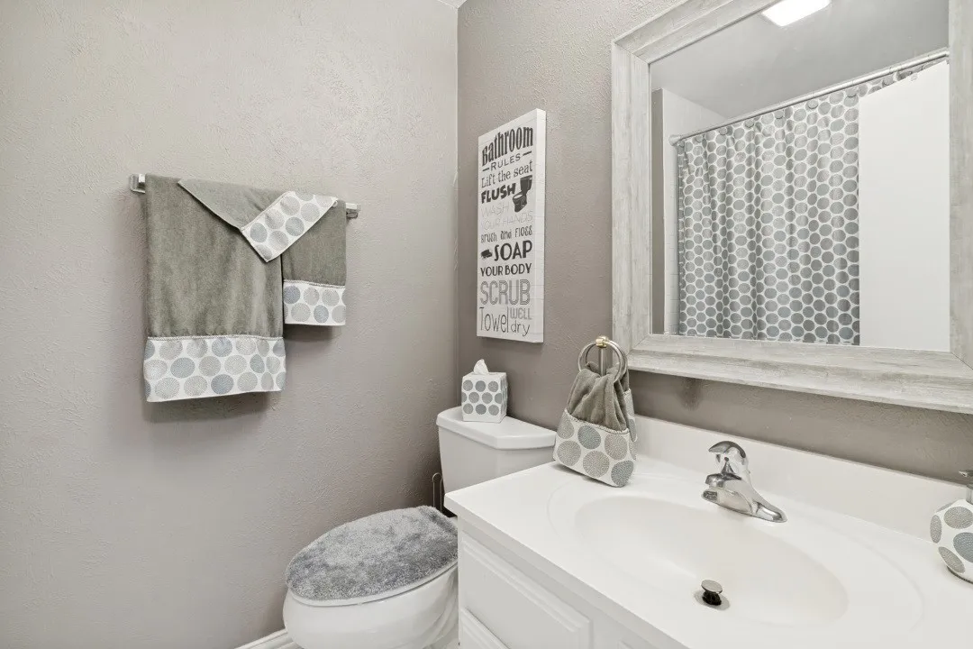 Bathroom featuring a white vanity with an integrated sink, polished chrome faucet, and a framed mirror