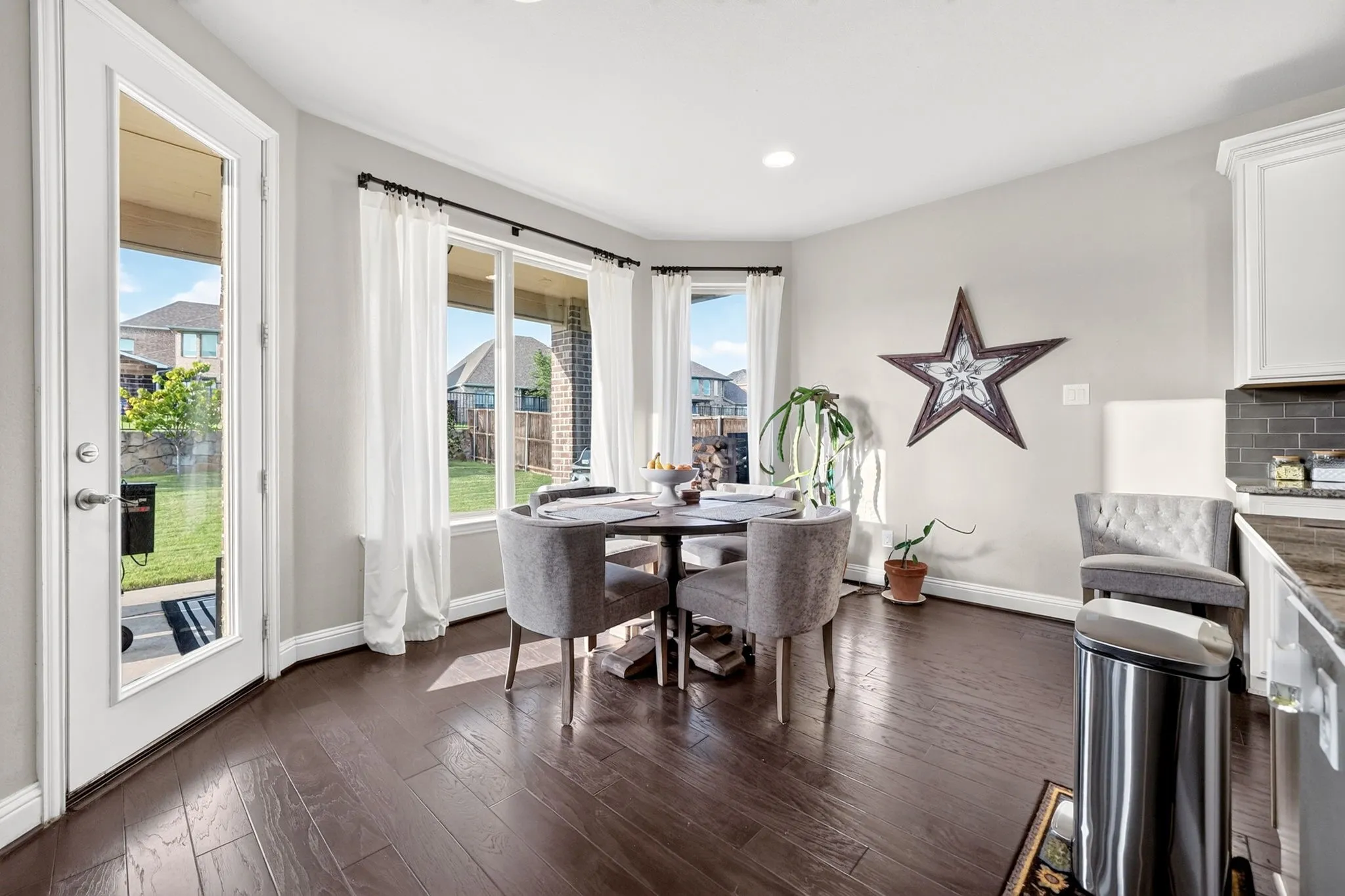 Open-concept dining area featuring dark wood-finish flooring, a wall of windows, and a glass-paneled door opening to the exterior