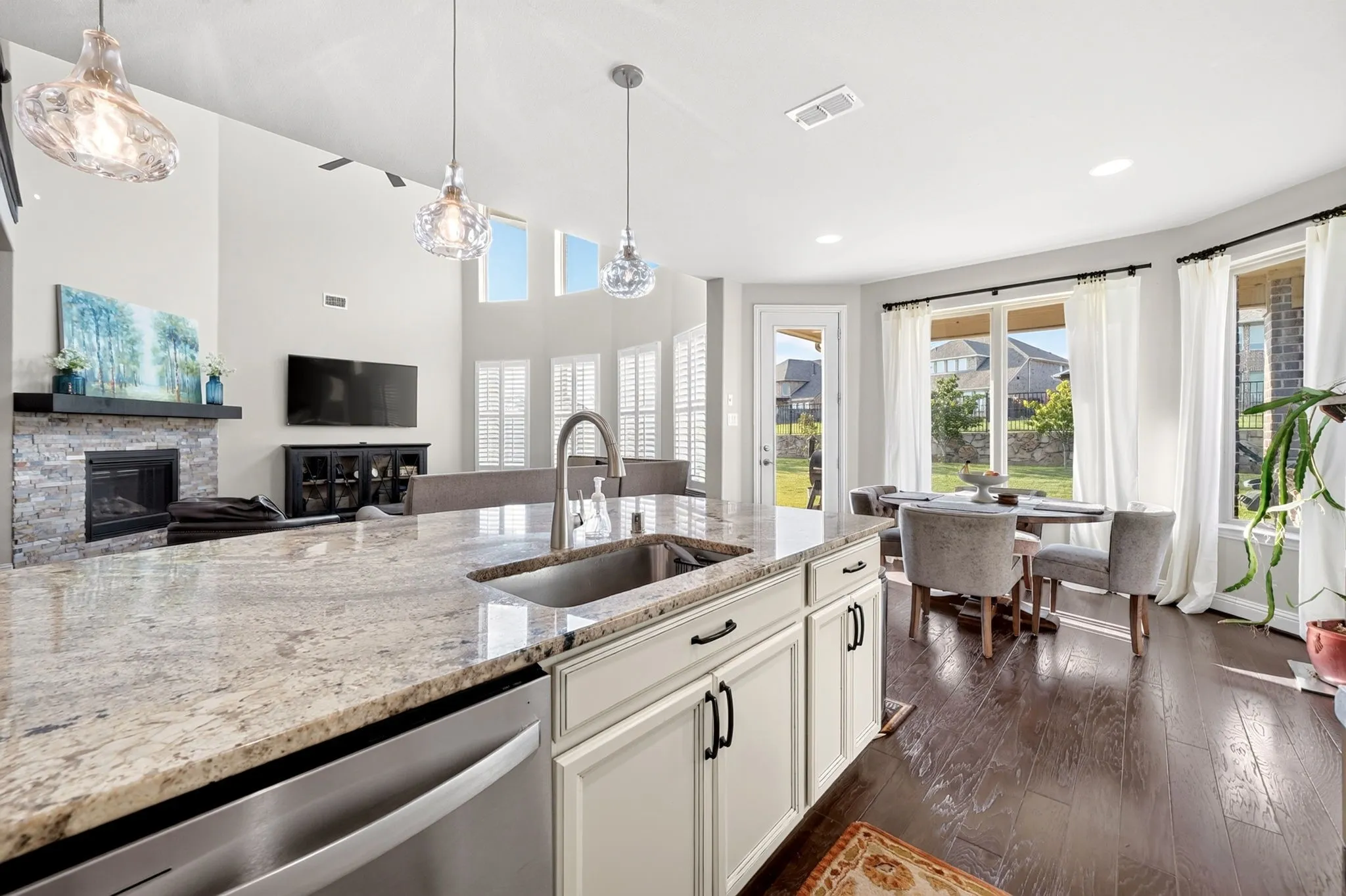 Kitchen island featuring a stainless steel undermount sink, a gooseneck faucet, and light-toned granite countertops