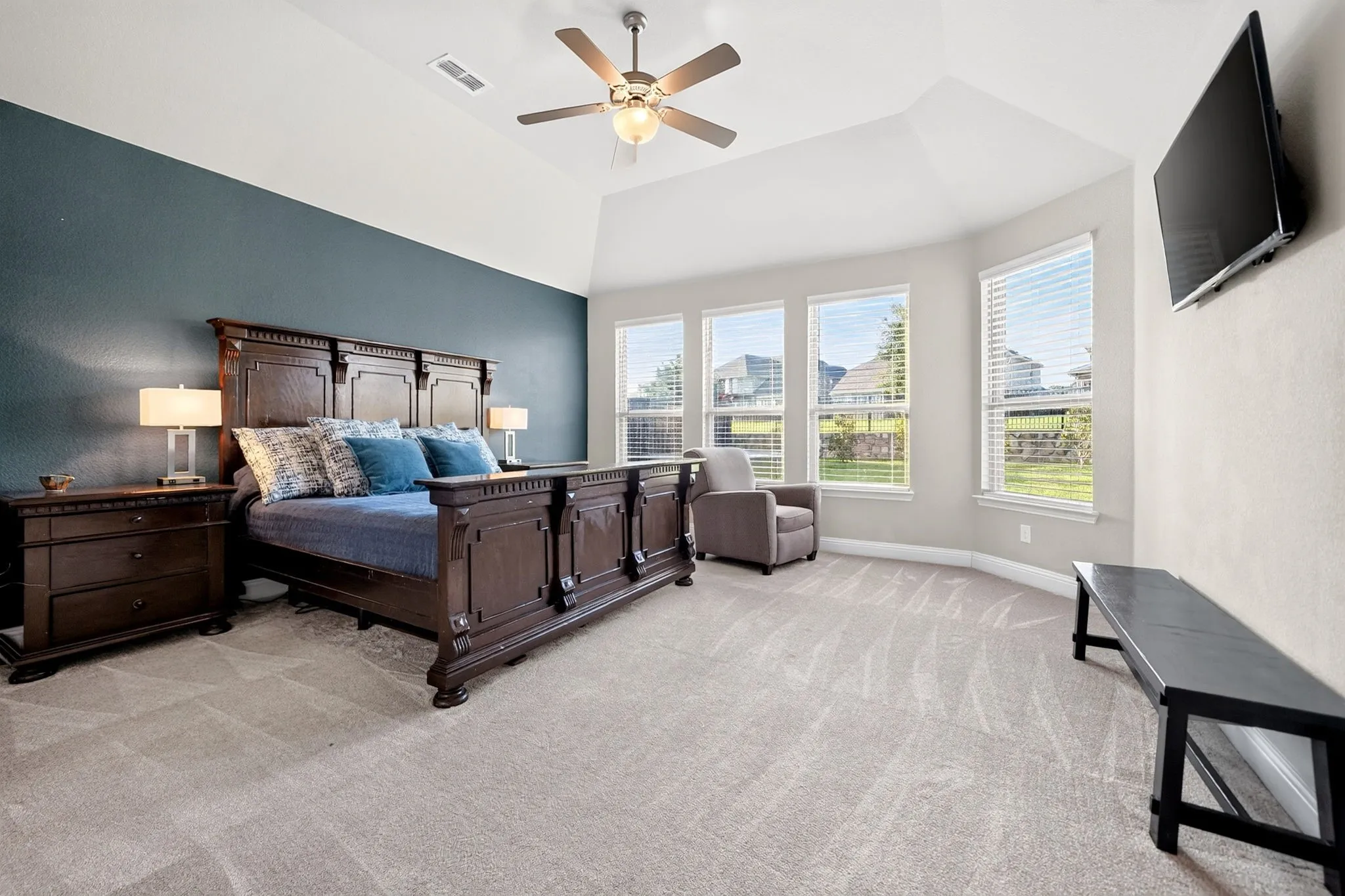 Expansive bedroom featuring vaulted ceilings, a ceiling fan with integrated lighting, and neutral-toned carpeting