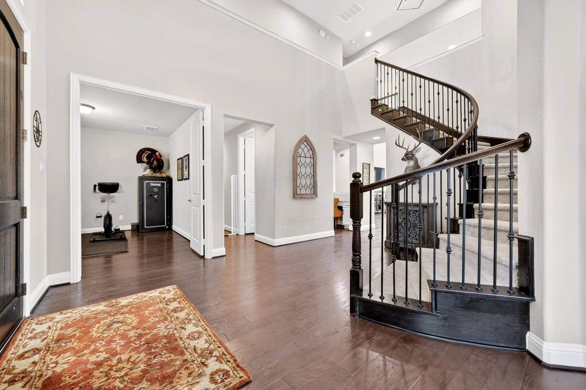 Two-story foyer featuring a grand spiral staircase with dark wood newel posts and wrought iron balusters, high ceilings, wood-finish flooring, and crown molding