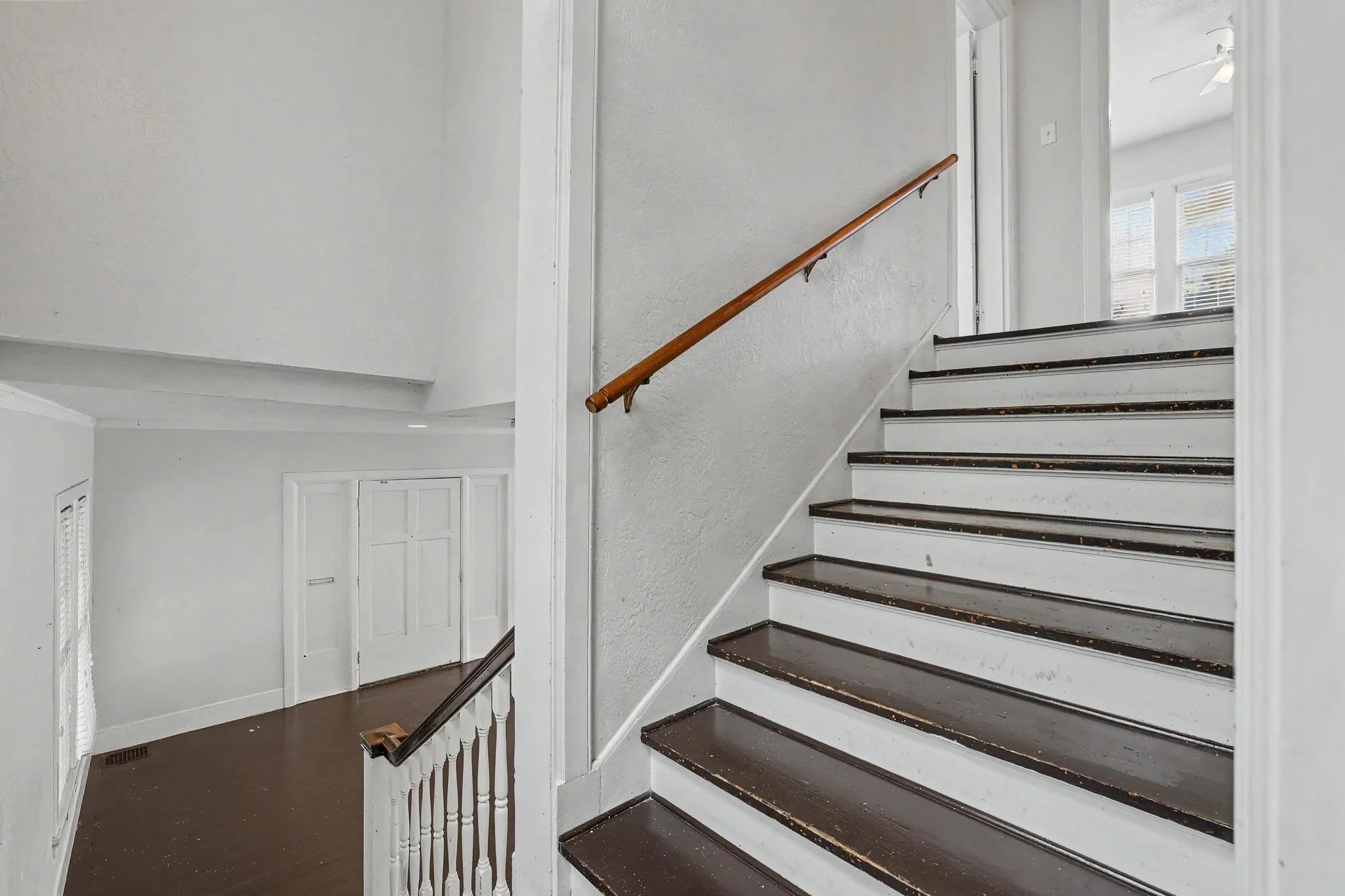 Staircase with dark-finish treads and white risers, featuring a wood handrail