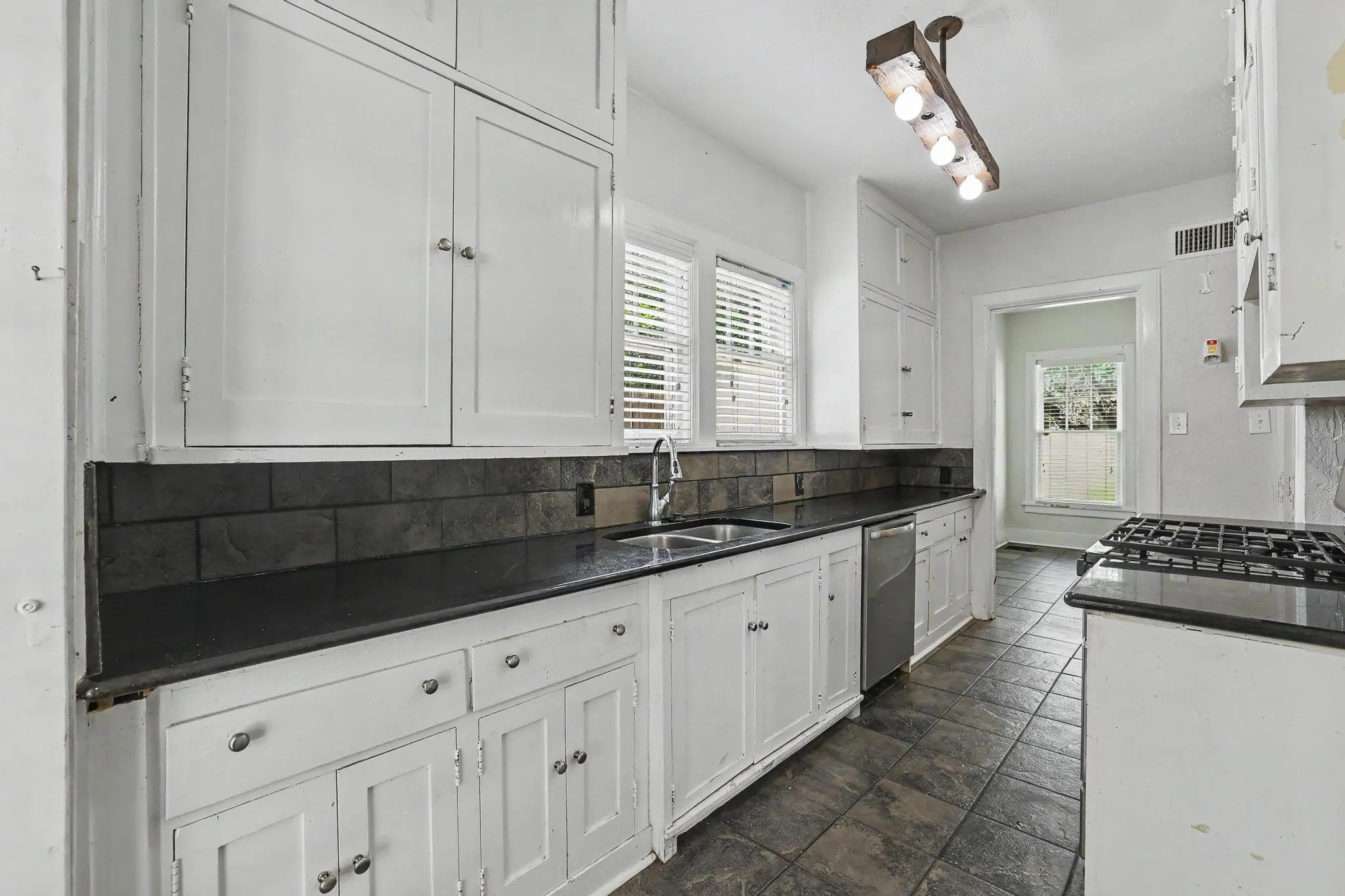 Kitchen featuring white cabinetry, dark stone countertops, and a subway tile backsplash