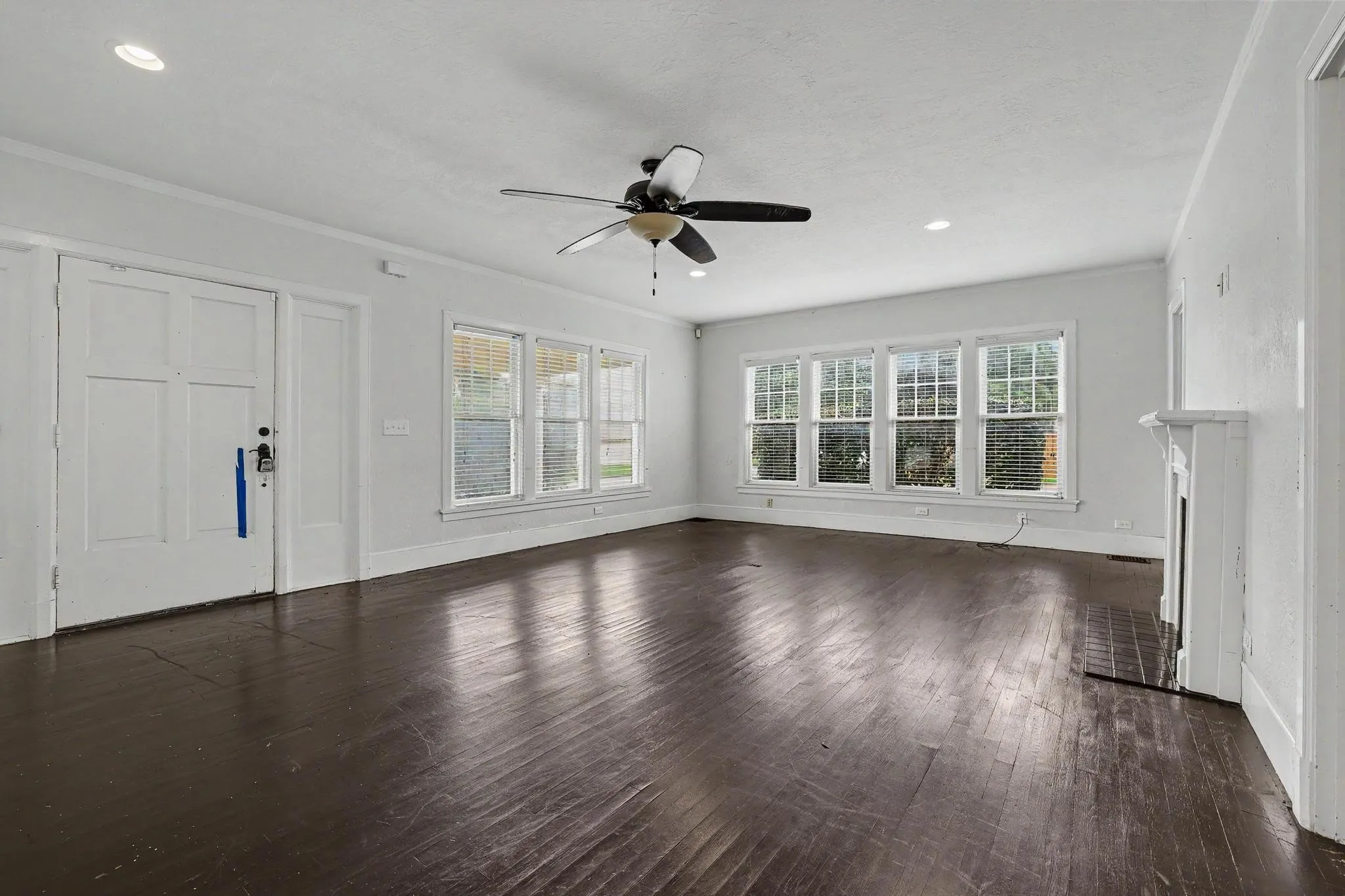 Spacious room featuring dark wood-finish flooring, a decorative fireplace with a tile hearth, and a multi-pane window wall