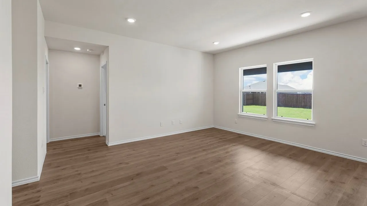 Spacious room featuring wood-finish flooring, recessed lighting, and two double-hung windows with roller shades