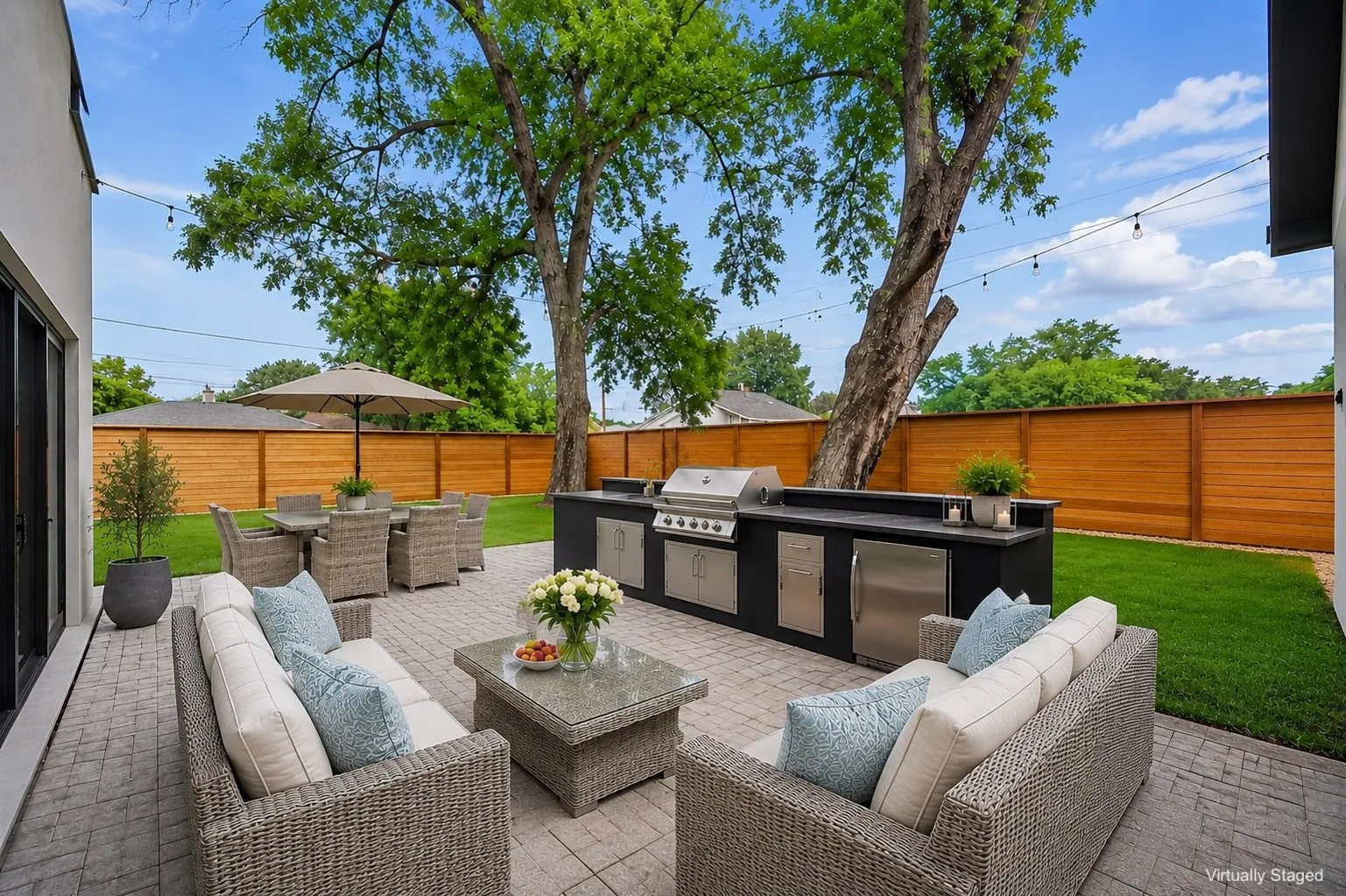 Outdoor living space featuring a paver patio with an integrated outdoor kitchen, stainless steel grill, and refrigerator