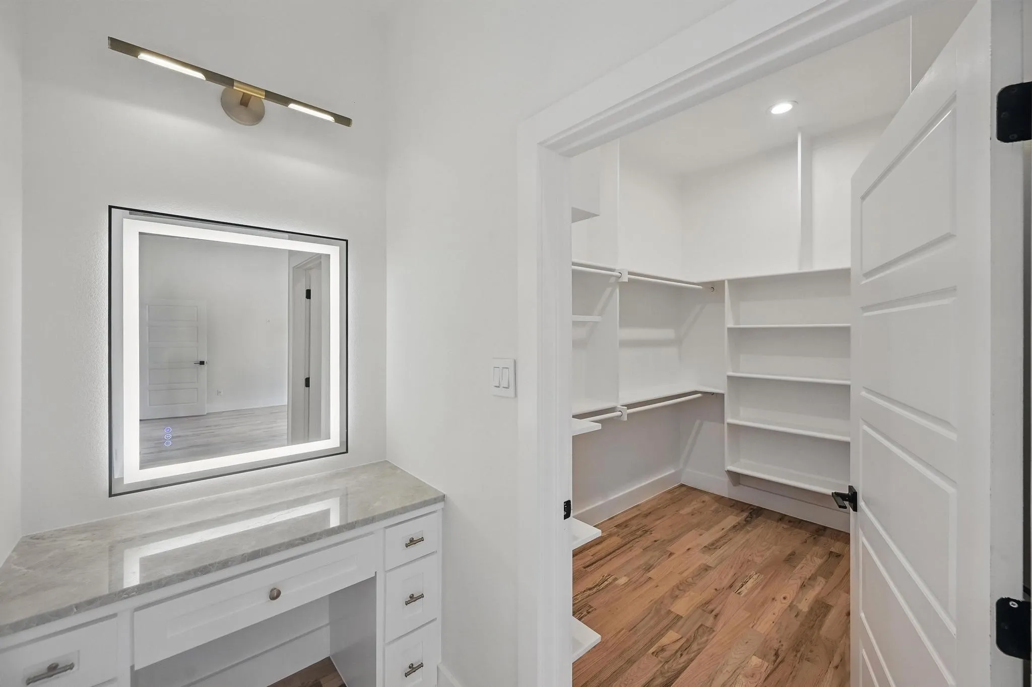 Built-in vanity with a stone countertop and an illuminated mirror