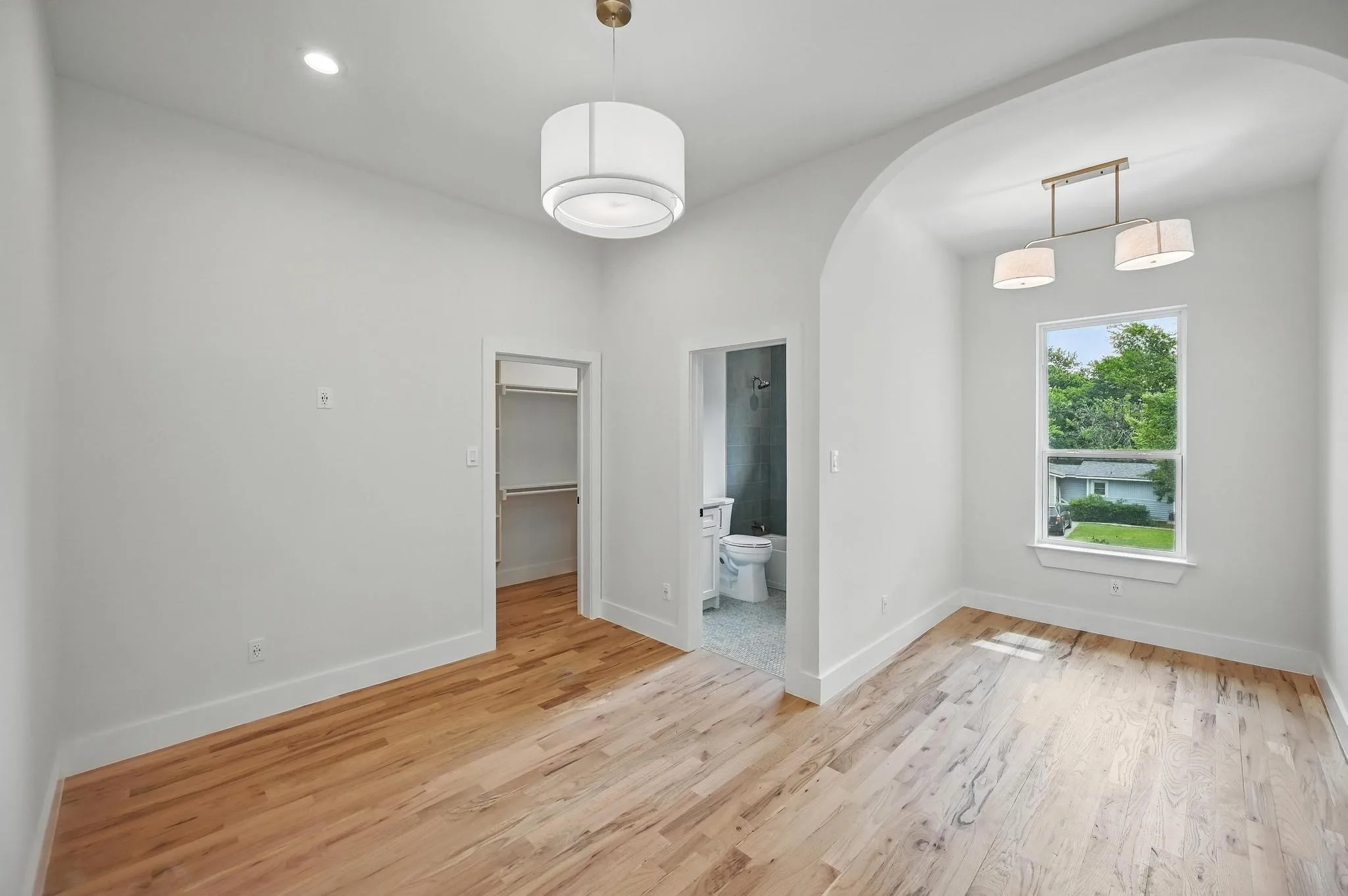 Hardwood-finish flooring extending into an arched alcove with a window