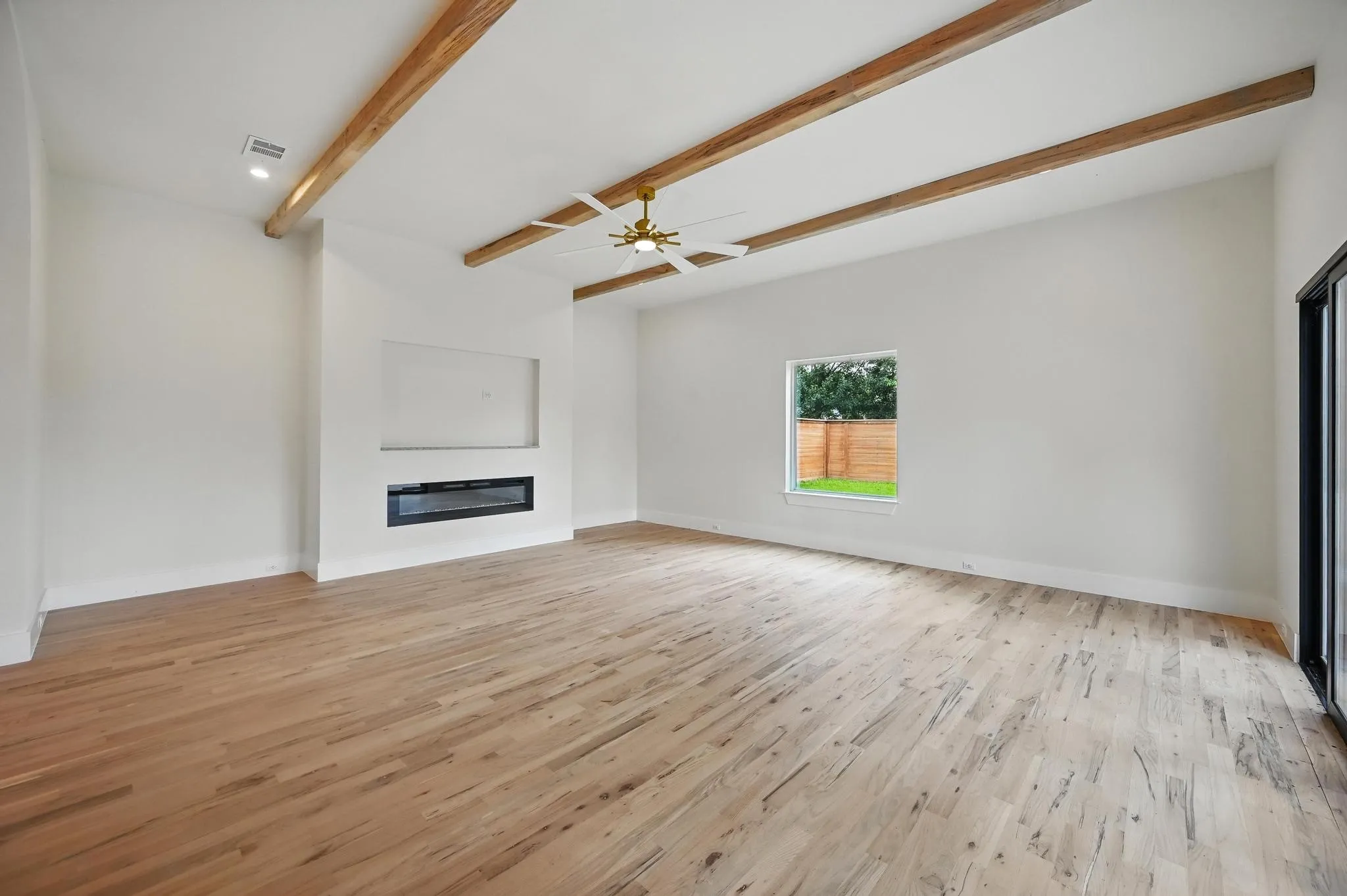 Spacious interior featuring wood-finish flooring, exposed ceiling beams, and a built-in electric fireplace