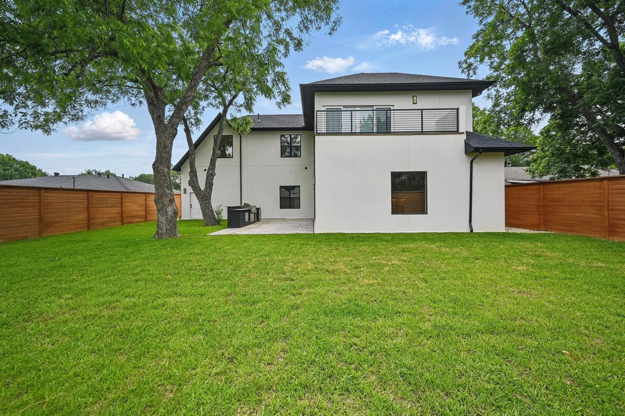 Expansive backyard featuring a manicured lawn, full privacy fencing, and mature trees