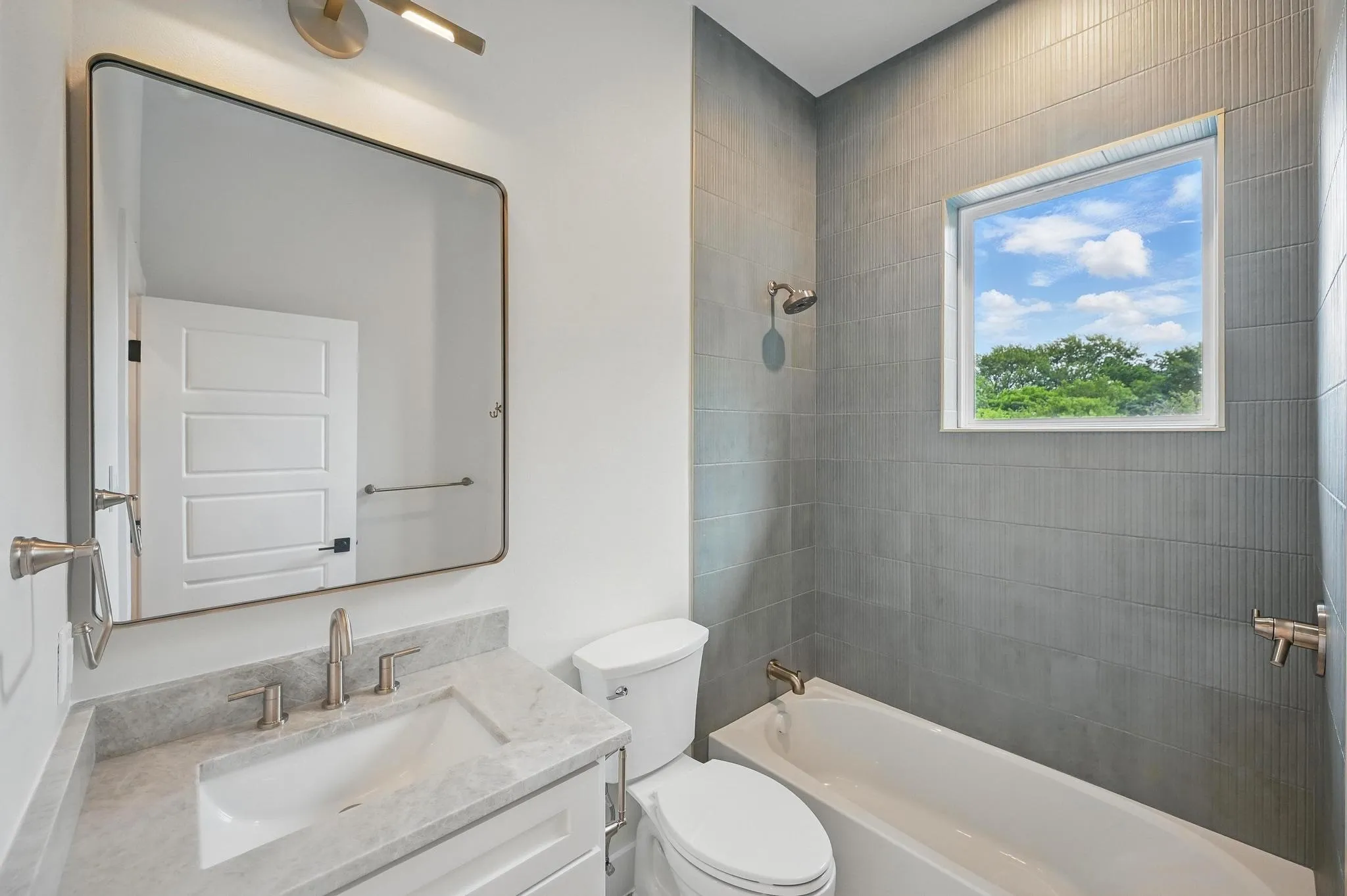 Bathroom featuring a white vanity with an undermount sink, a light-toned countertop, and a contemporary mirror