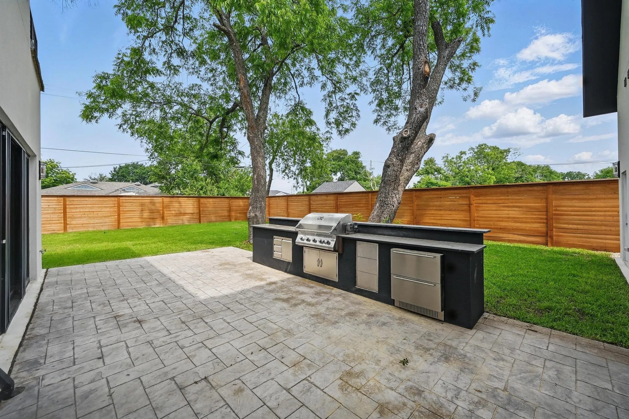 Spacious backyard featuring a large stamped concrete patio and a built-in outdoor kitchen with stainless steel appliances
