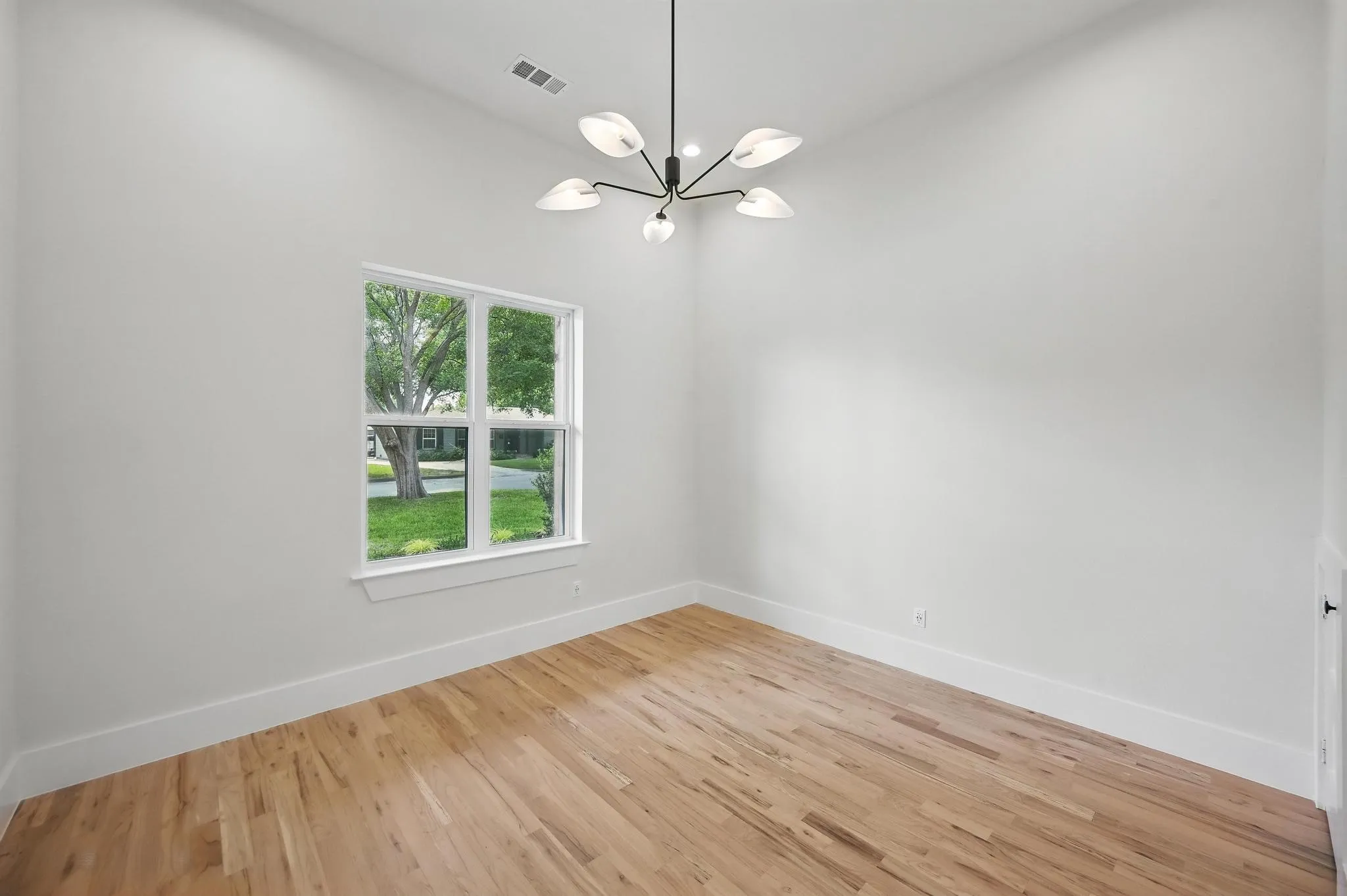 Room featuring wood-finish flooring, a contemporary ceiling light fixture, white baseboards, a white window frame, and neutral wall paint