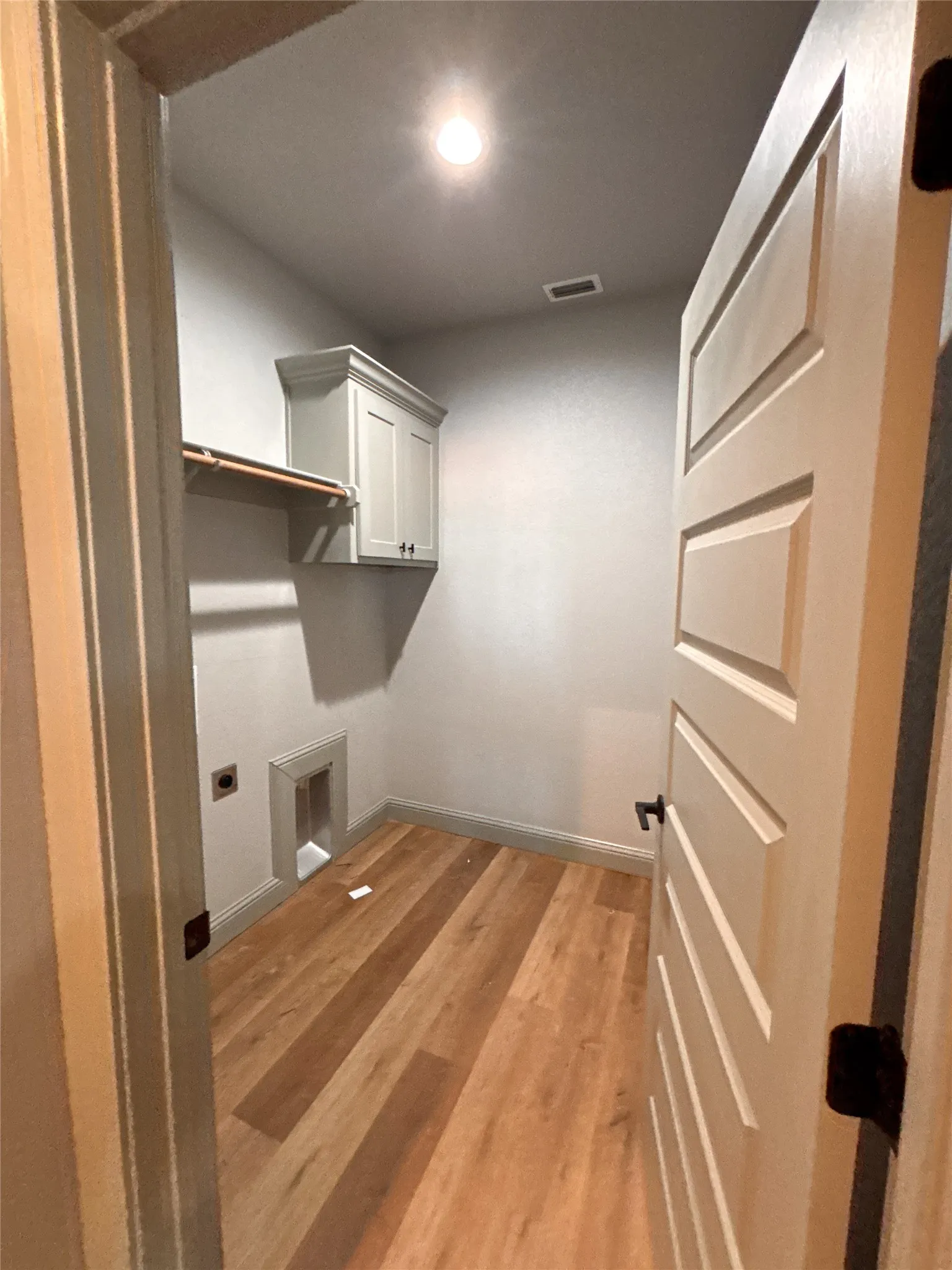 Dedicated laundry area featuring wood-finish flooring
