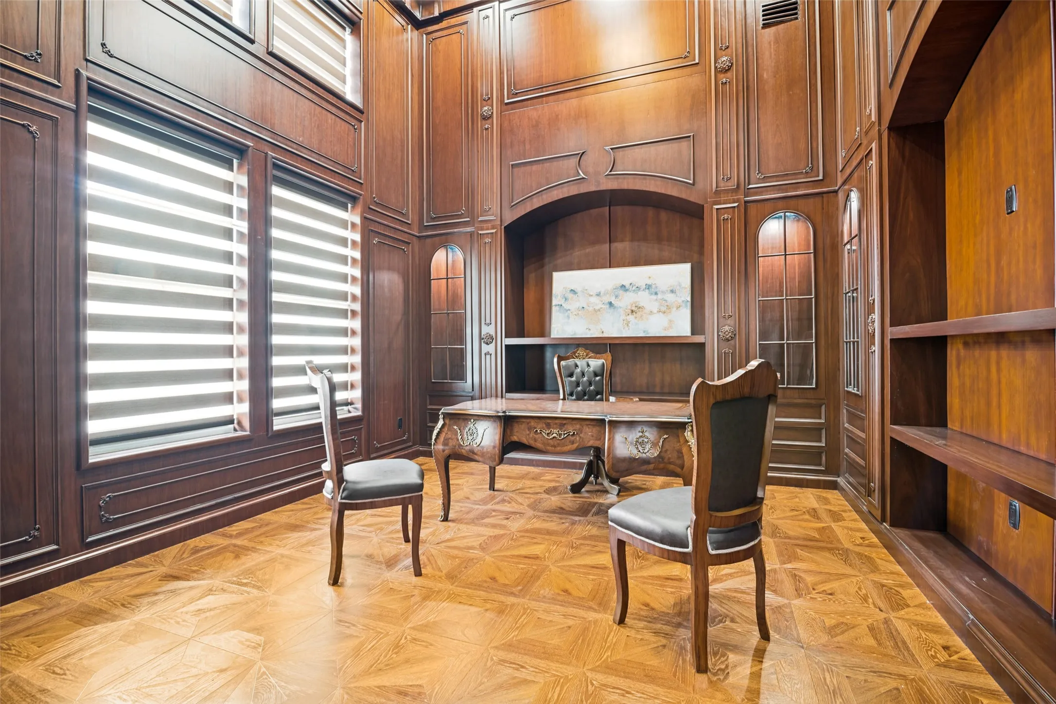 Custom wood paneling, parquet wood-finish flooring, built-in shelving, high ceilings, and arched accents define this elegant interior space
