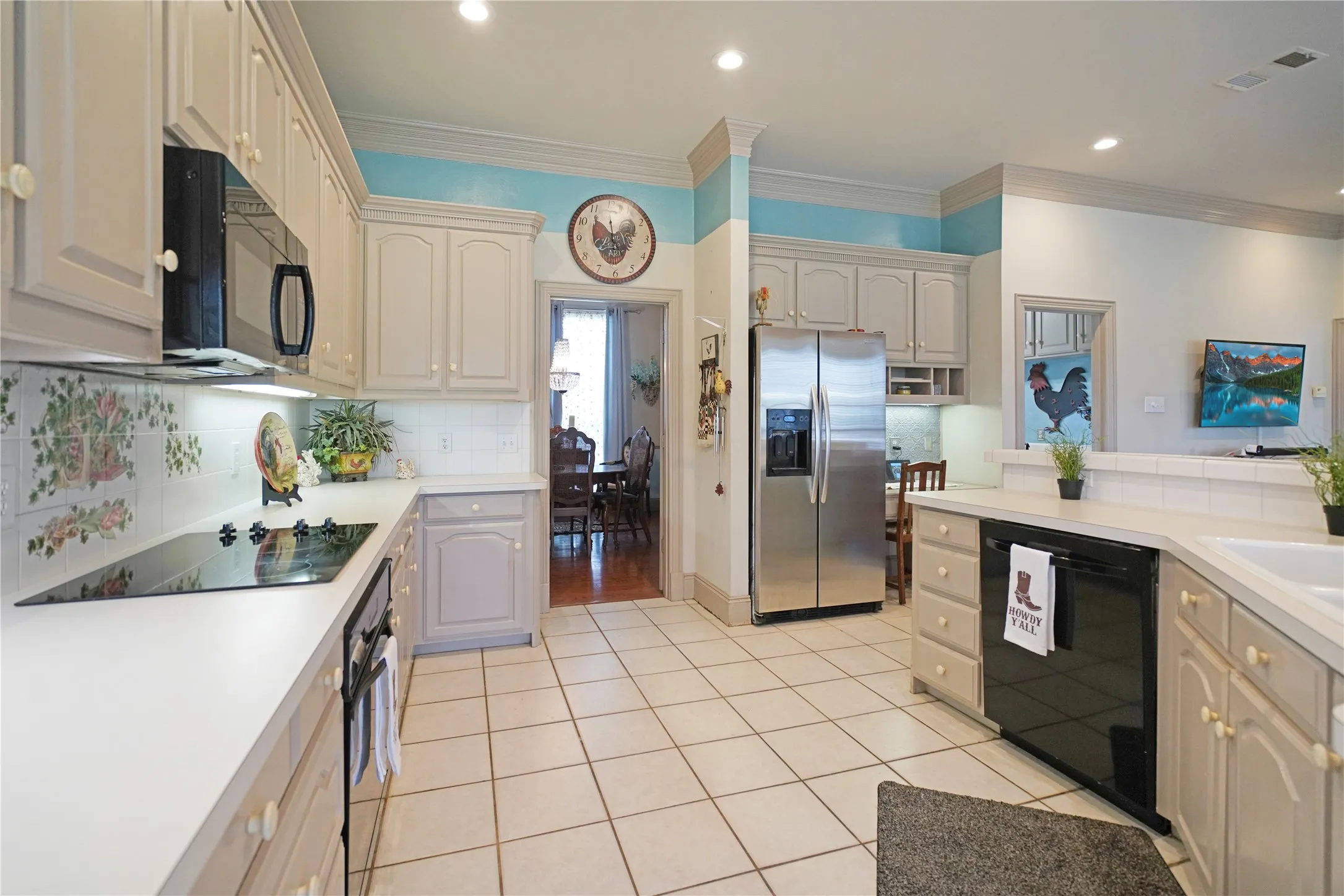 Spacious kitchen featuring light cabinetry, white countertops, tile flooring, a built-in range, and a stainless steel refrigerator