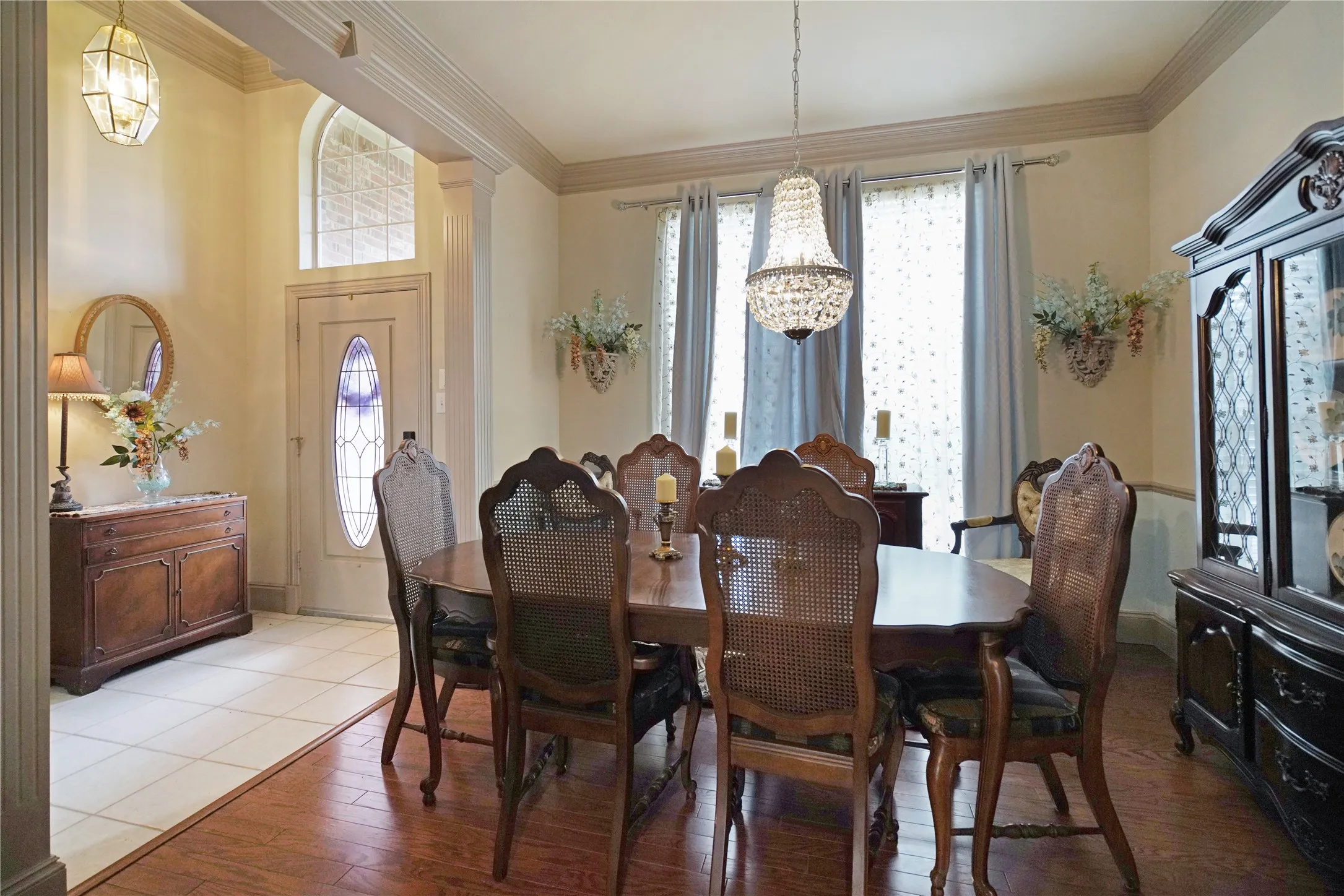 Formal dining space featuring wood-finish flooring, an ornate crystal chandelier, and large windows with drapery