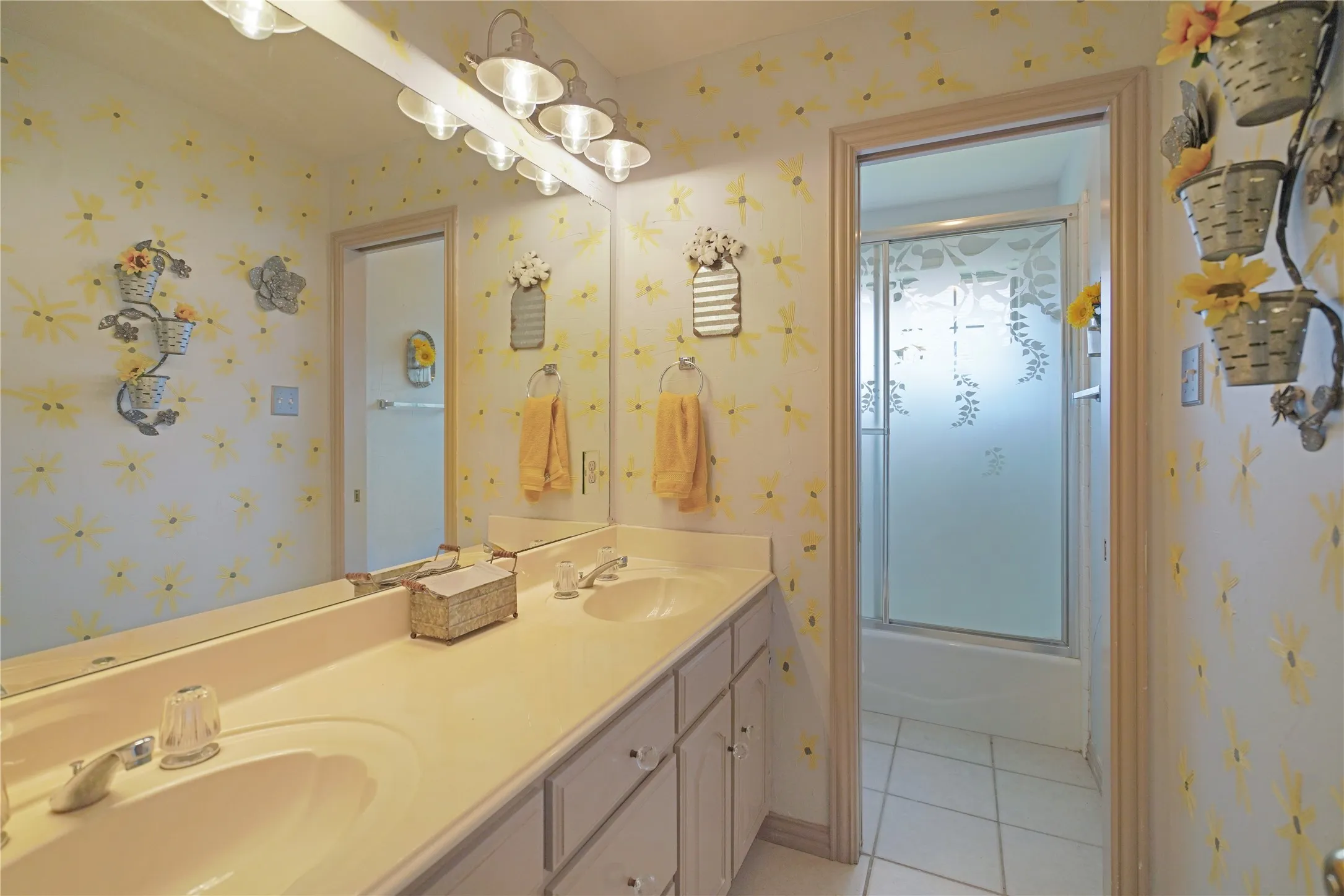 Dual vanity with integrated sinks and ample countertop space, complemented by an overhead multi-bulb light fixture
