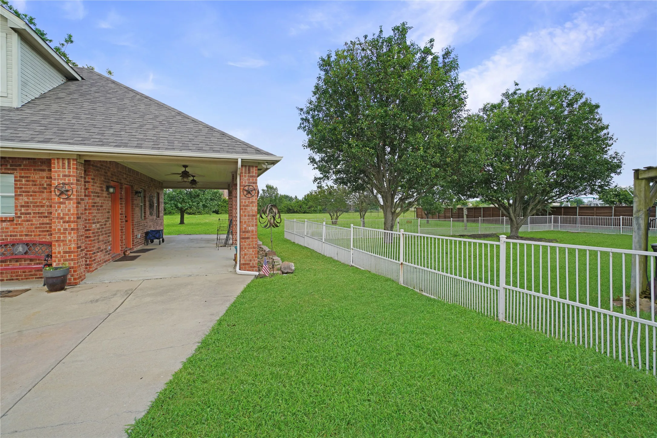 Red brick exterior with a covered concrete patio featuring ceiling fans