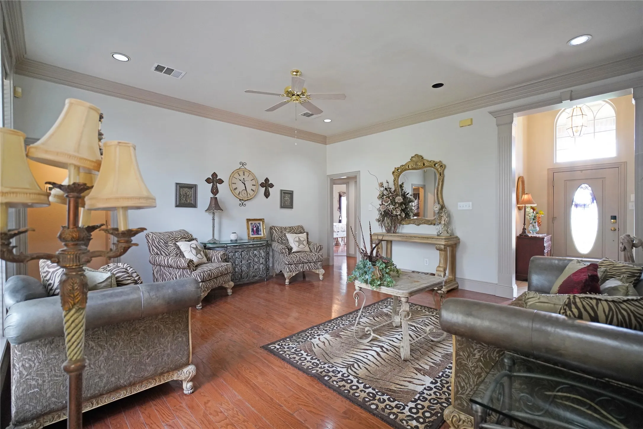 Spacious living area featuring wood-finish flooring, crown molding, a ceiling fan, and recessed lighting